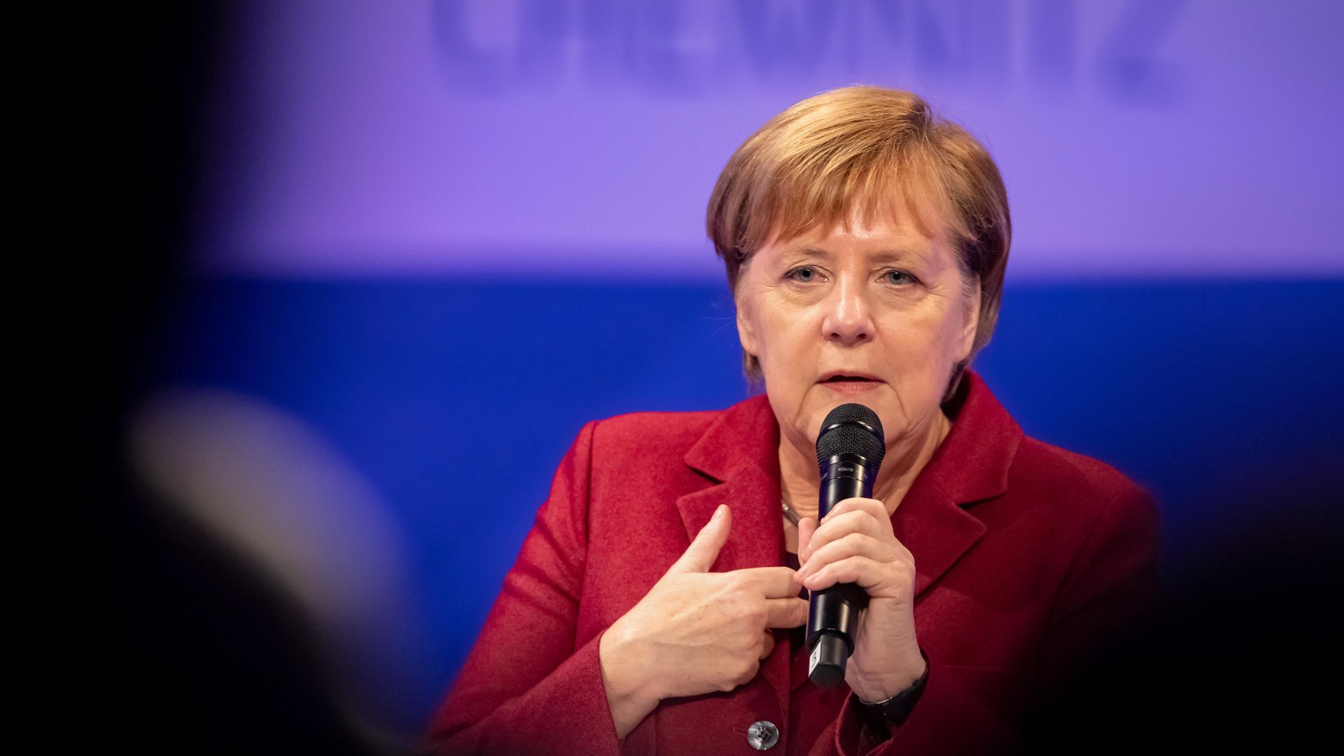 Angela Merkel speaks to an audience with a microphone