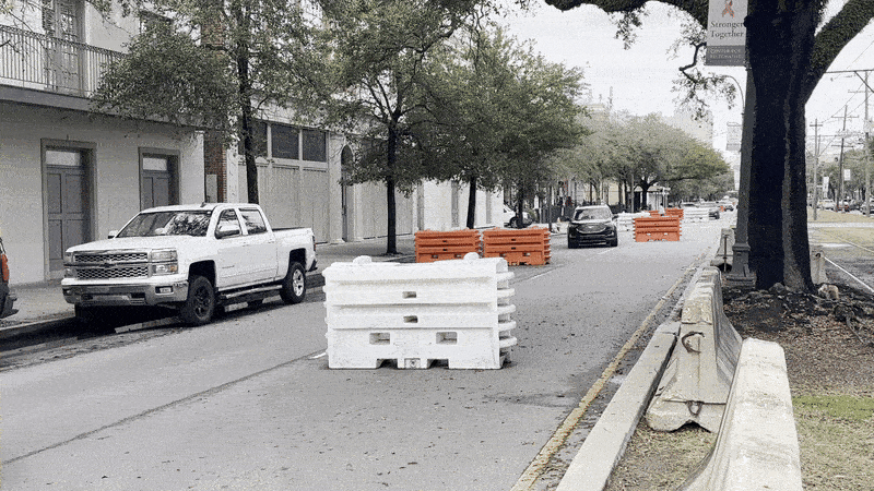 Photo shows a car going around orange and white barricades.