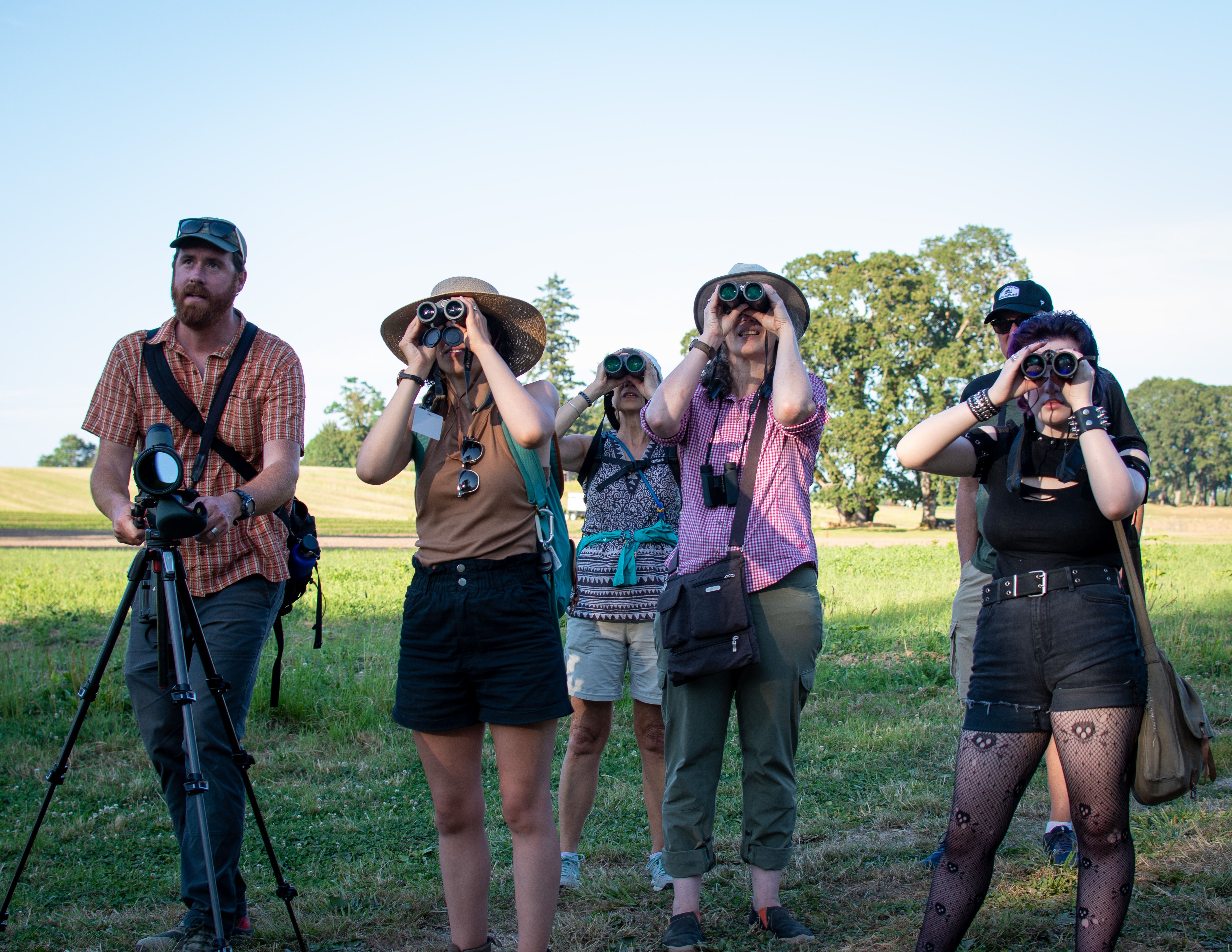 A photo of people looking through binoculars at birds.