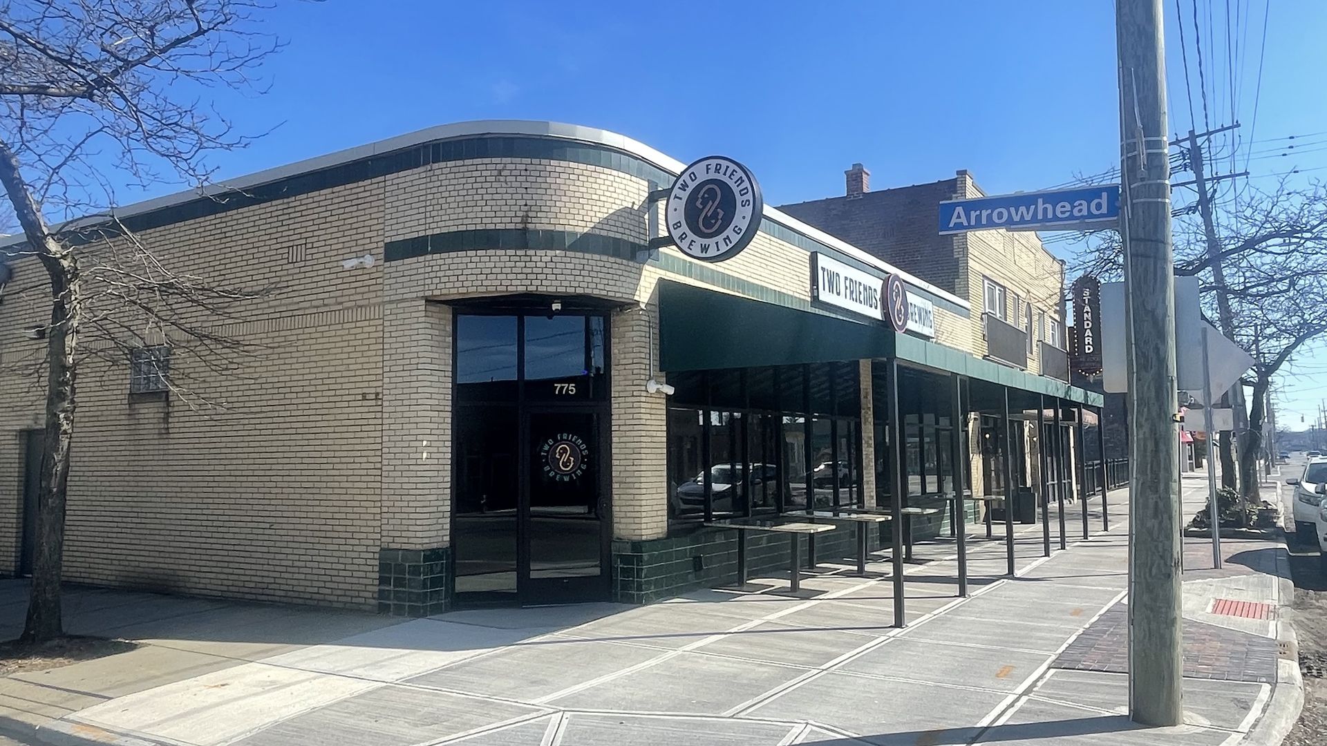 An exterior of a building converted to a brewery. White brick with green trim. 