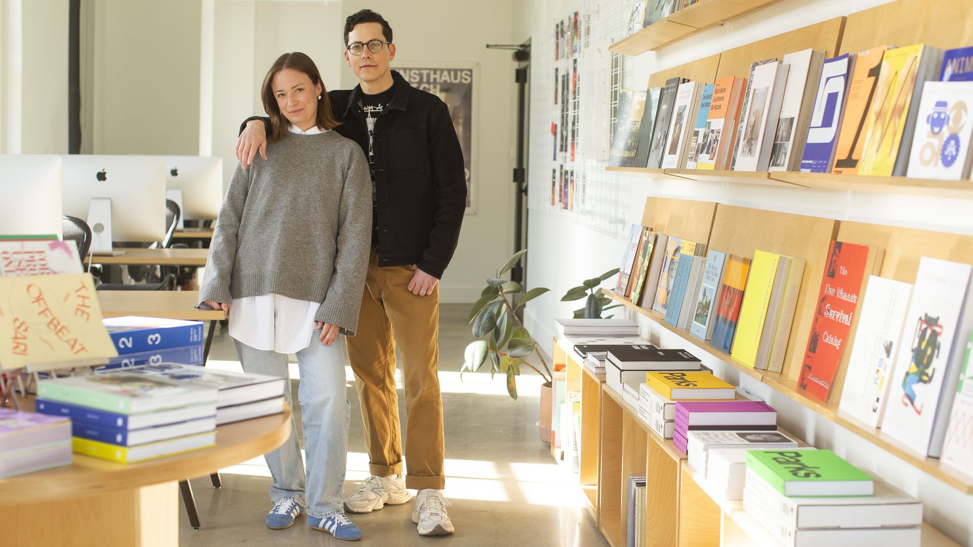 The couple standing in the design studio next to books