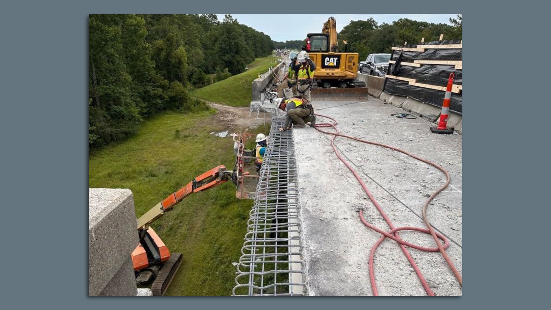 Photo shows a workers rebuilding the East Pearl River Bridge. Heavy equipment is on the bridge deck and below it.