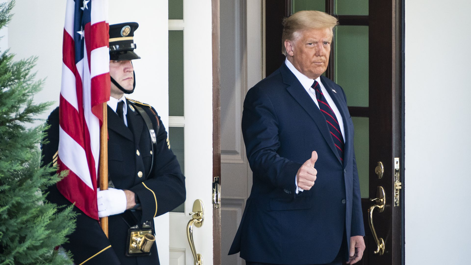 Trump wearing a suit steps out of a doorway