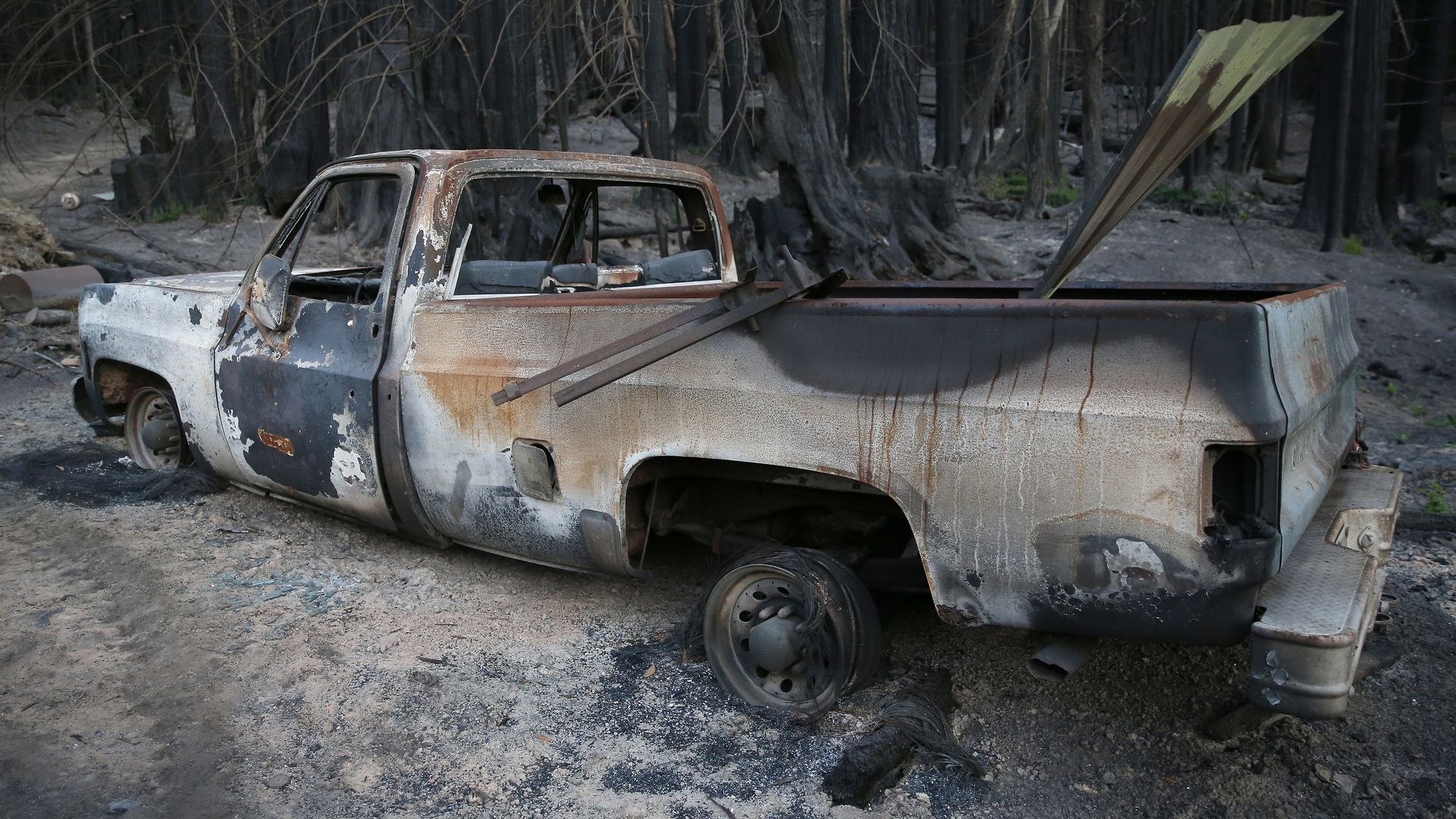 A burned truck is seen as Satchel MacLennan surveys the damage to his family's property in Last Chance, Calif.