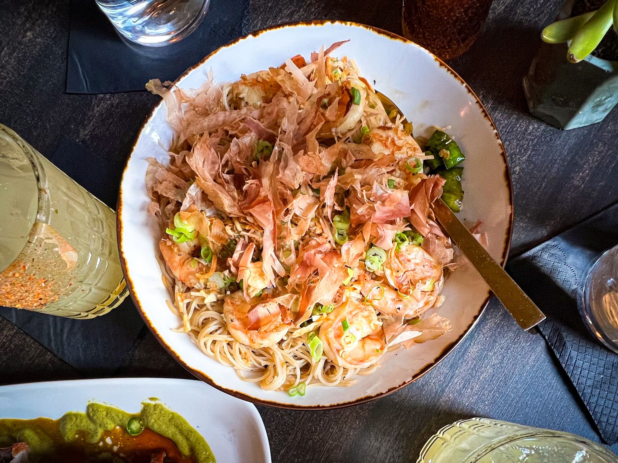 An ivory bowl of a dish comprised of noodles and shrimp.
