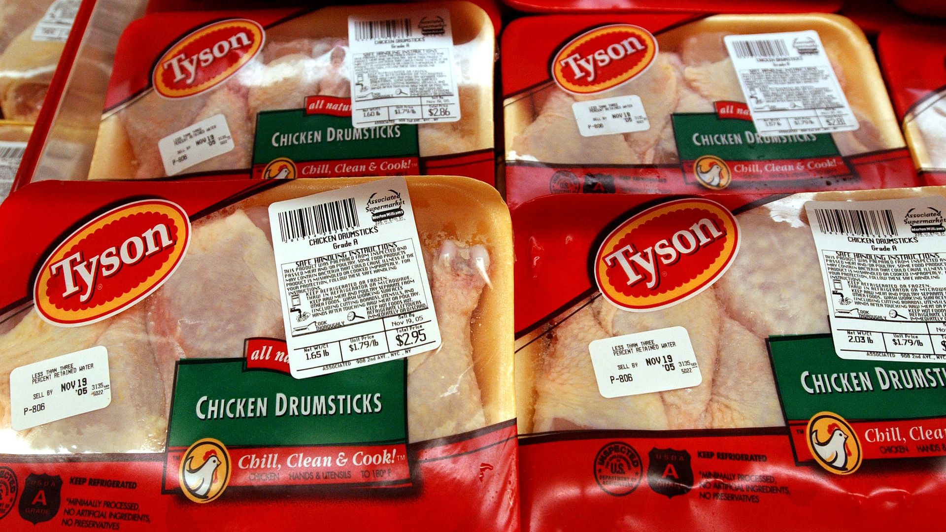In this image, four packages of frozen chicken drumsticks are shown in a grocery store.