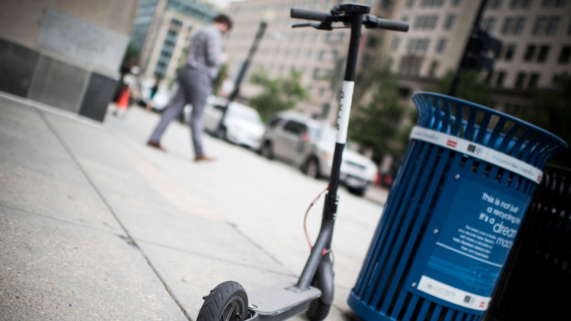 Electric scooter by a trash can. 