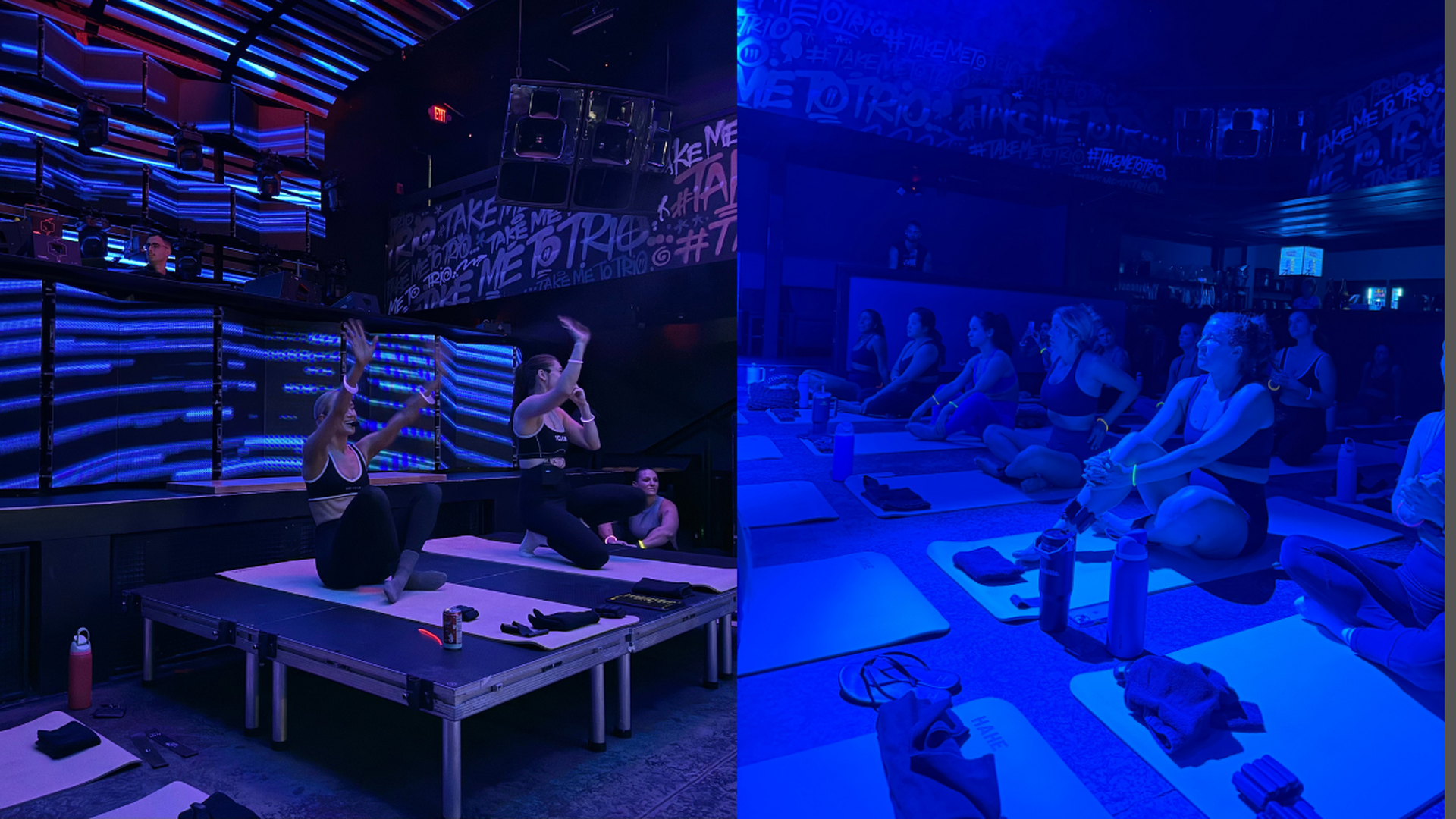 People participating in a nighttime yoga class inside a club with blue and purple neon lighting, some sitting on mats while two instructors lead from an elevated platform.