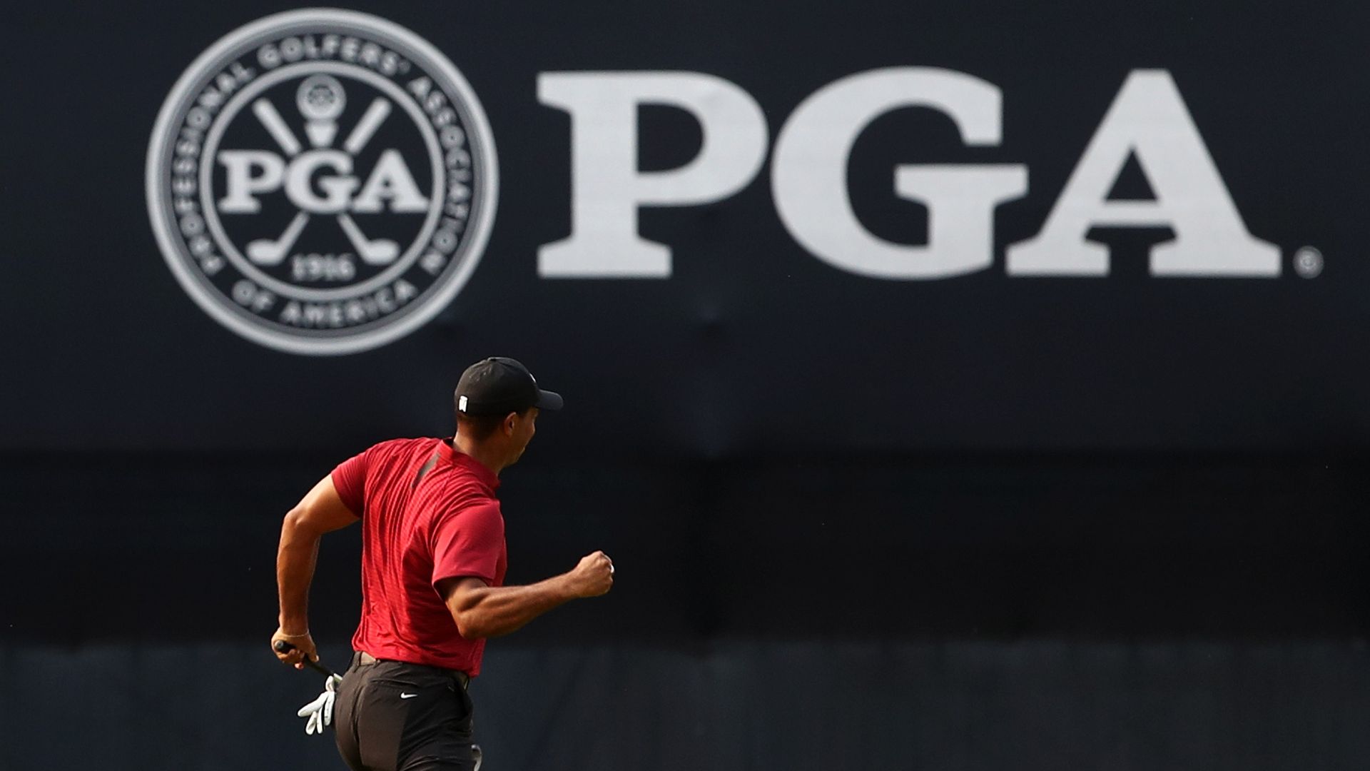 PGA Tour member Tiger Woods celebrates a putt in front of a PGA Tour sign.