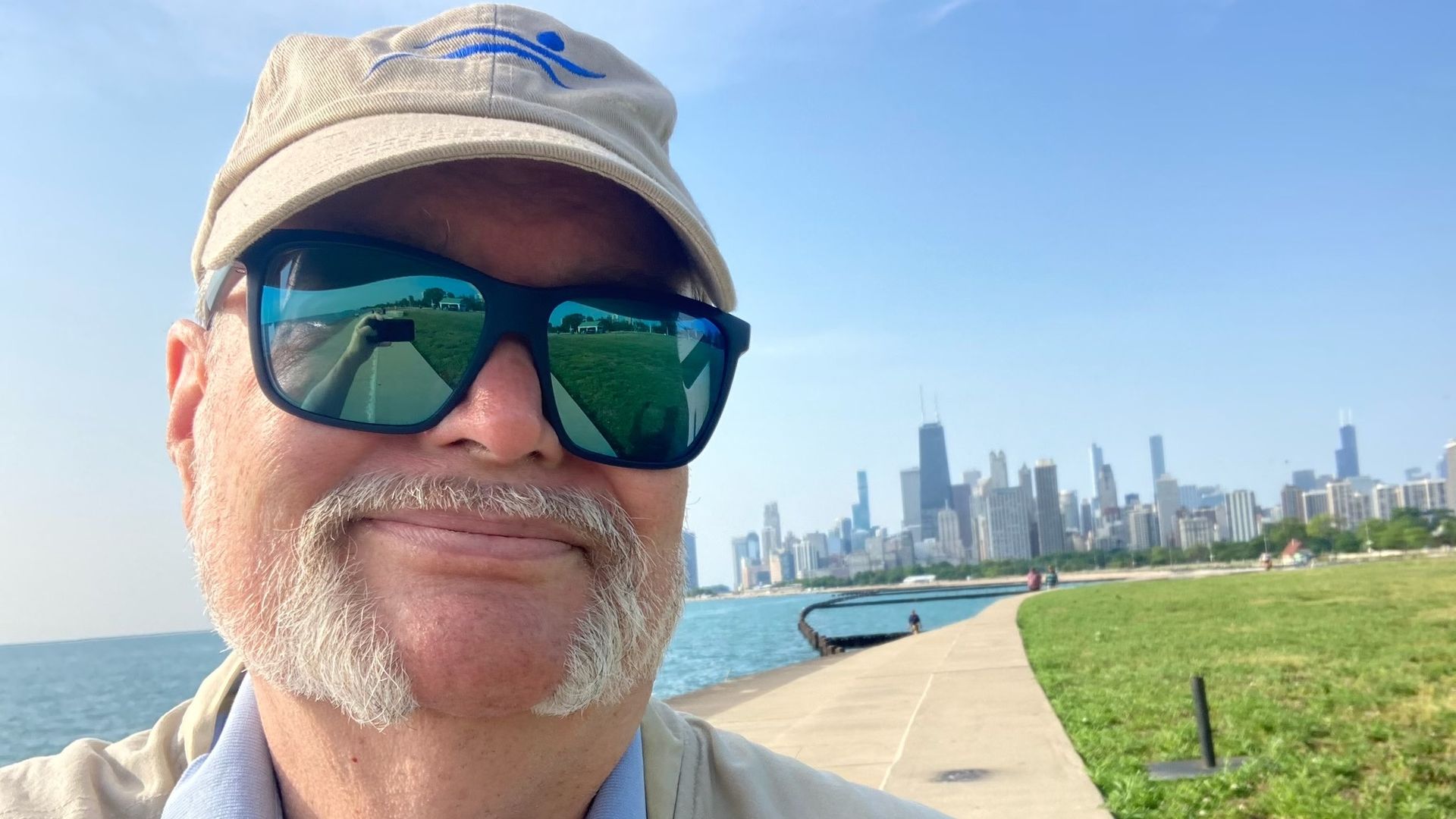 Photo of a man posing in front of a lake and skyscrapers. 