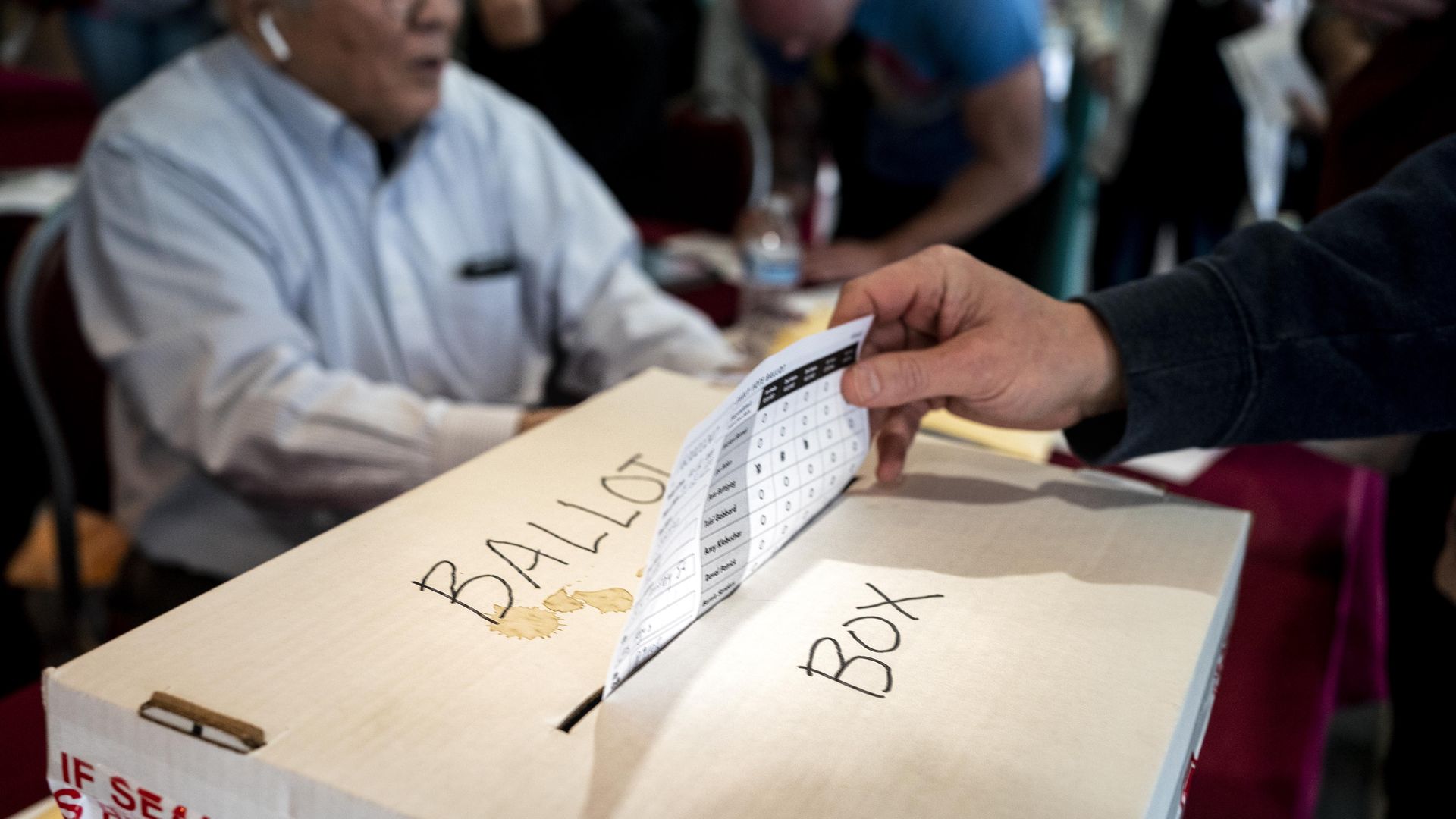 Picture of someone placing their ballot inside a ballot box.