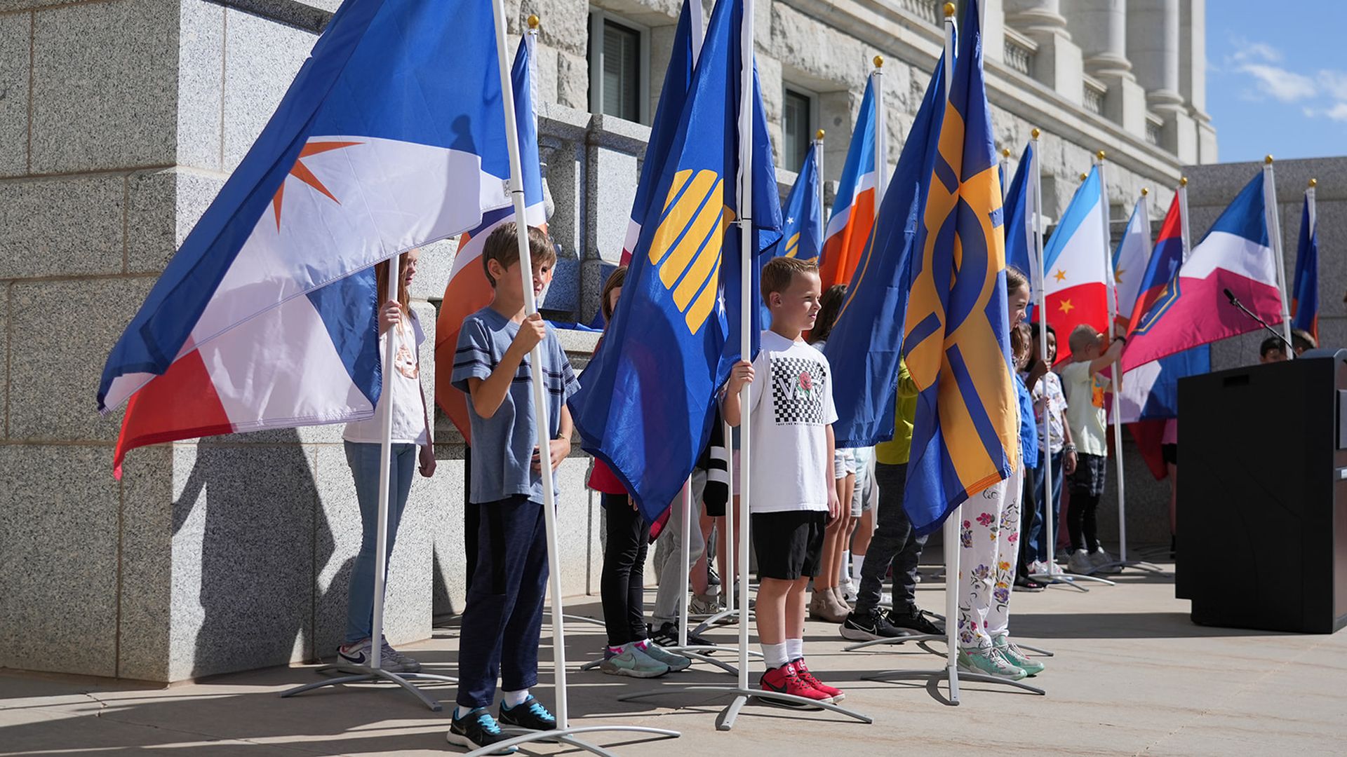 Children holding Utah State Flag proposals outside the state Capitol Building.