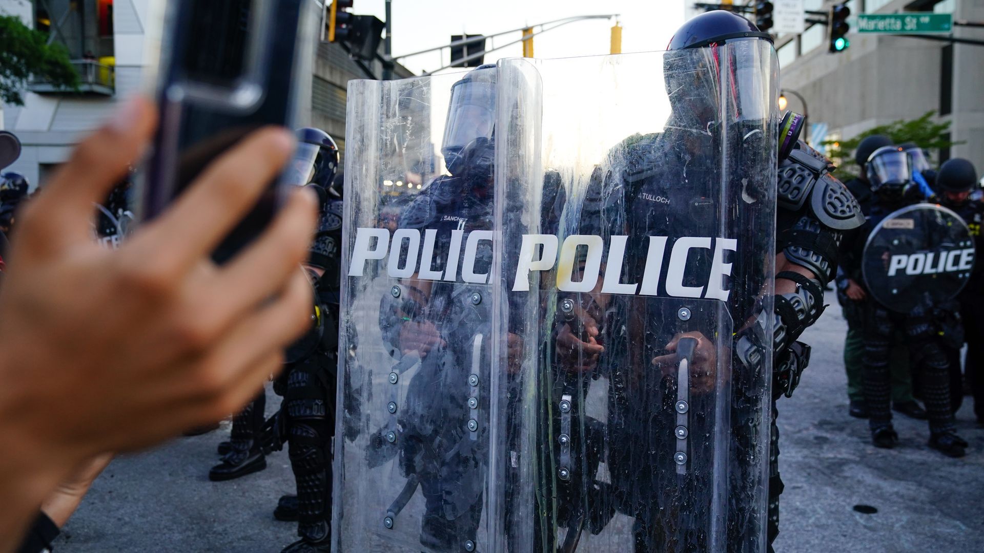 A man records video of a police line during a 2020 Atlanta protest in response to the police killing of George Floyd in Minnesota. Photo: Elijah Nouvelage/Getty Images