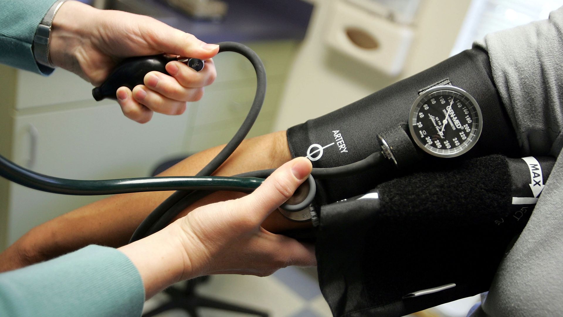 A doctor readers a blood pressure gauge.