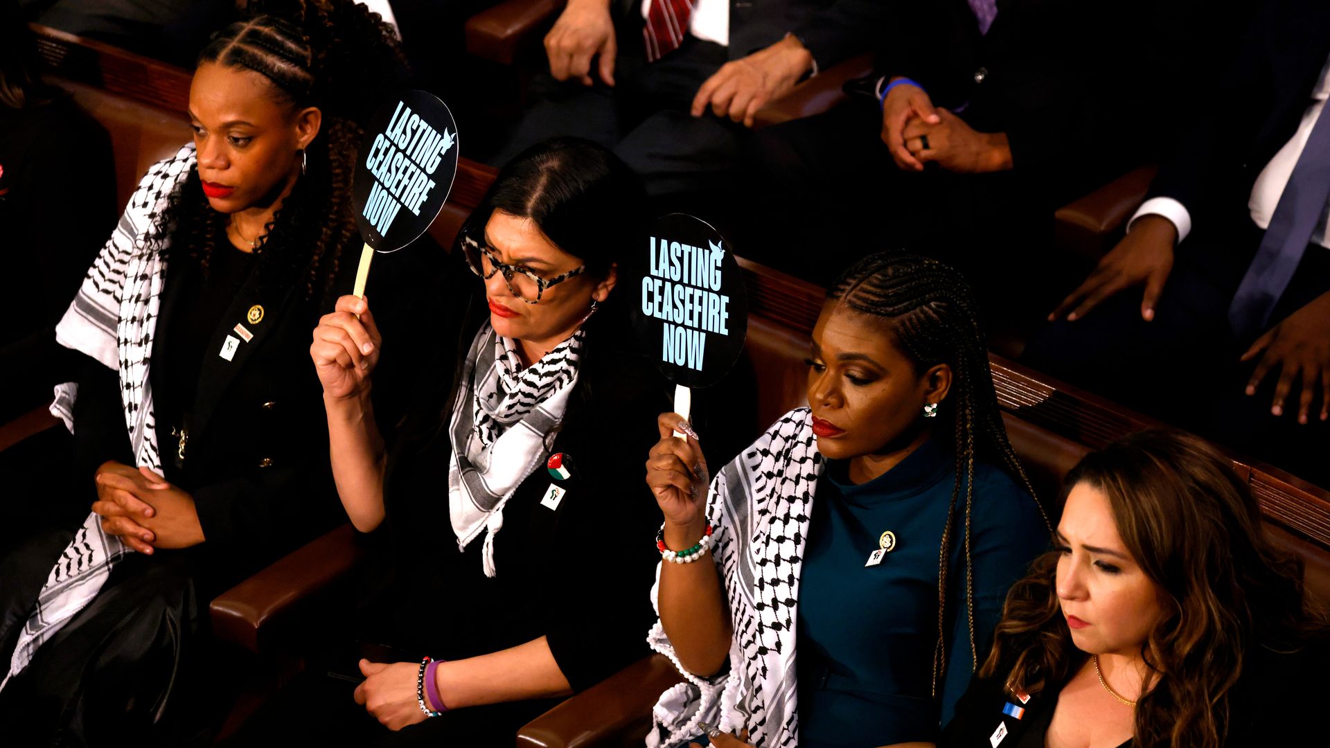 Rep. Rashida Tlaib(D-Mich.), center, and Rep. Cori Bush (D-Mo.) center right, hold up signs calling for a ceasefire during the State of the Union address  on March 7, 2024. 
