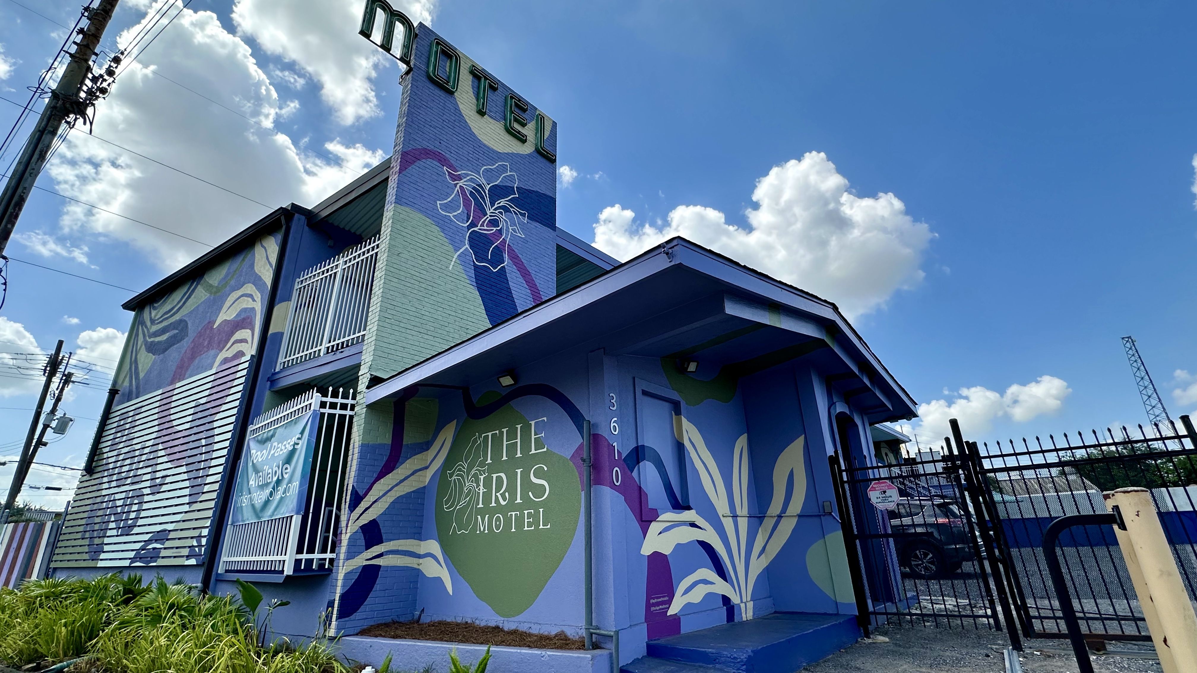 Photo shows the outside of the Iris Motel with a purple plant mural.