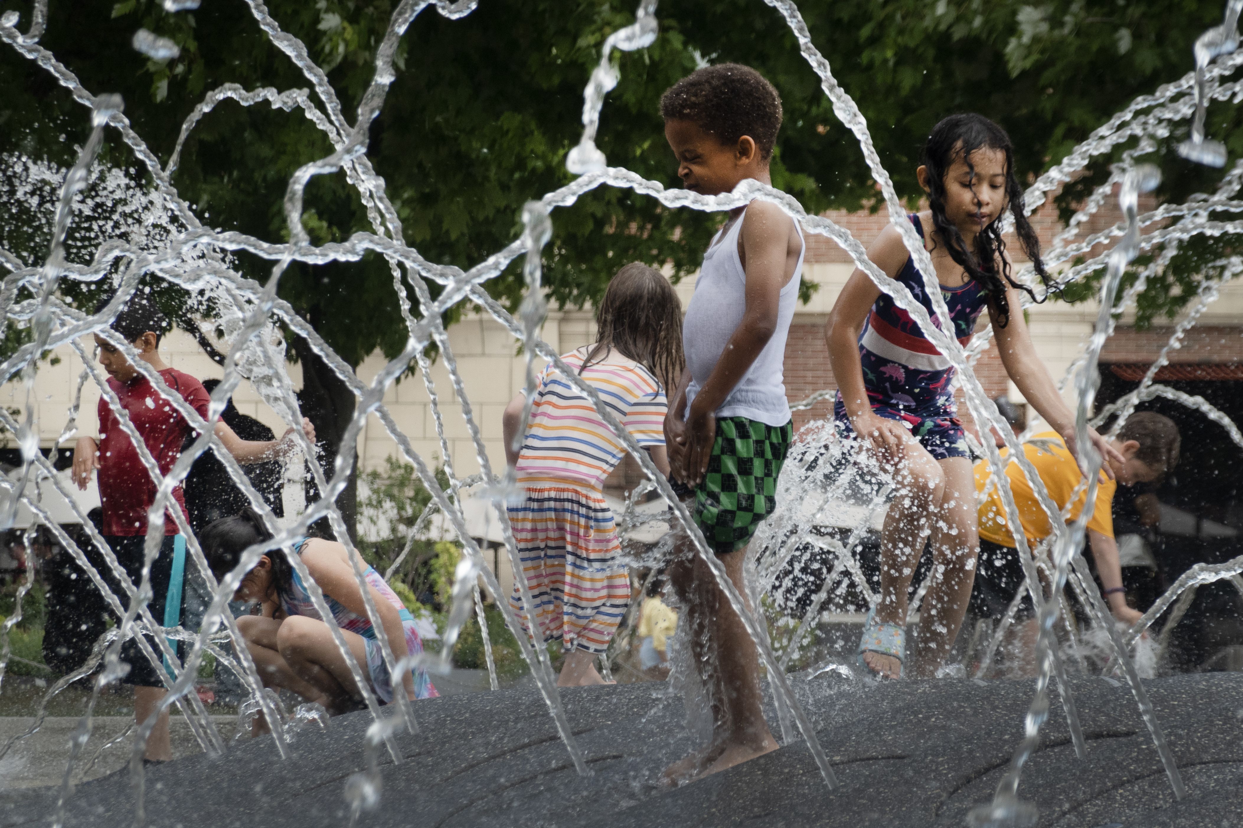 Kids playing ing a fountain.