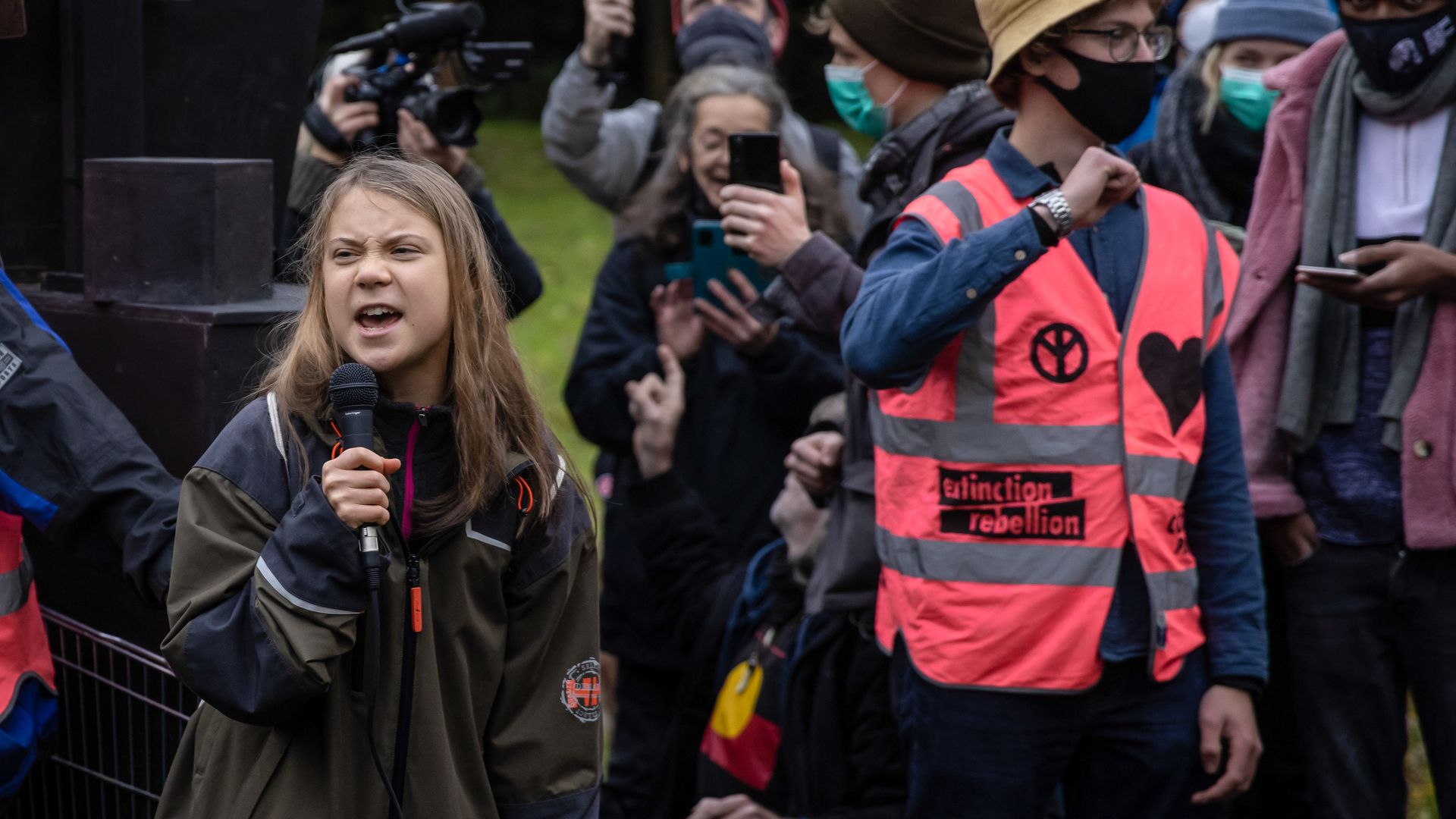 Photo of Greta Thunberg speaking into a mic at an outdoor climate protest