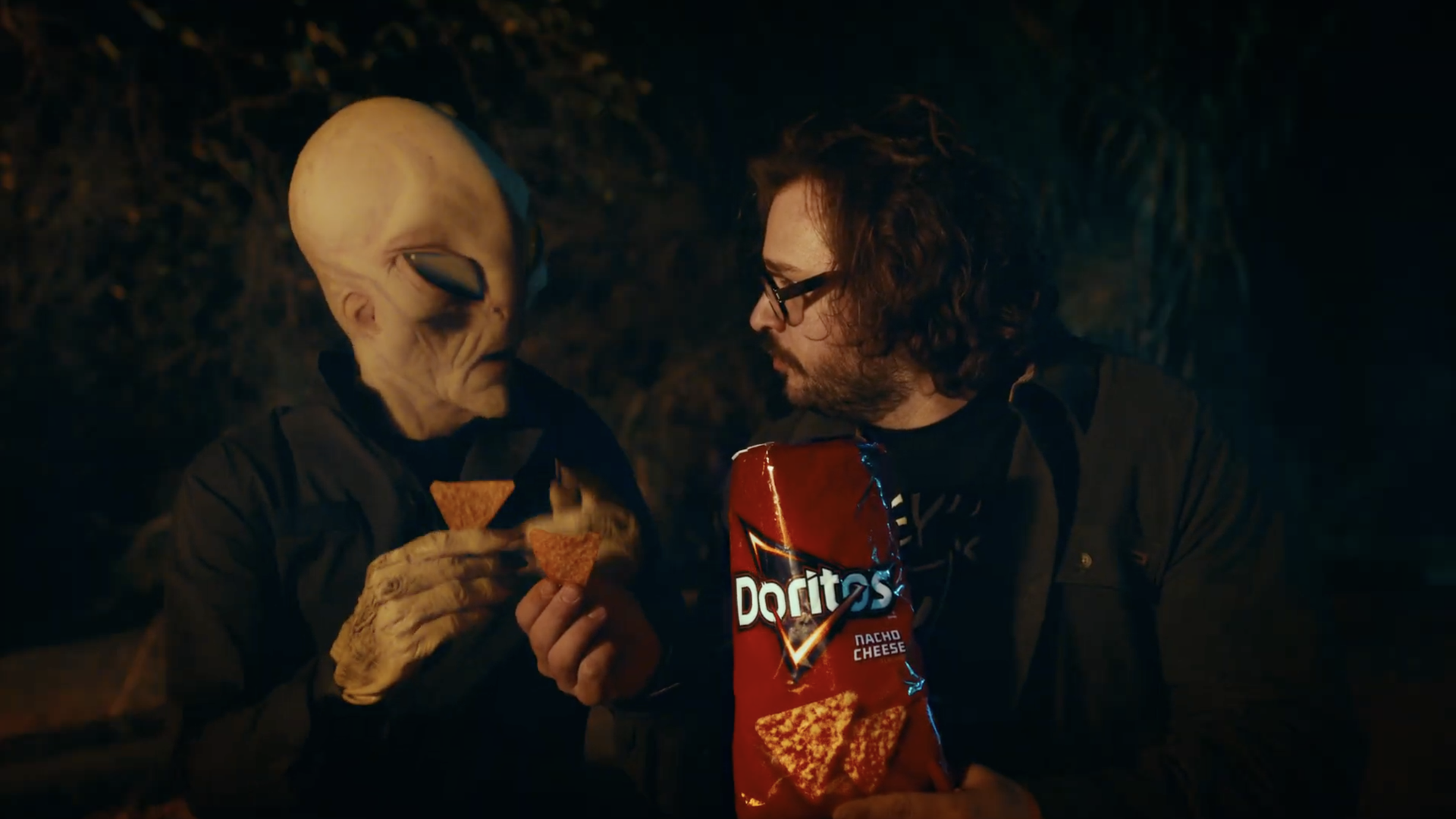 An alien and a man share a bag of Nacho Cheese Doritos in a screenshot of an upcoming Super Bowl ad