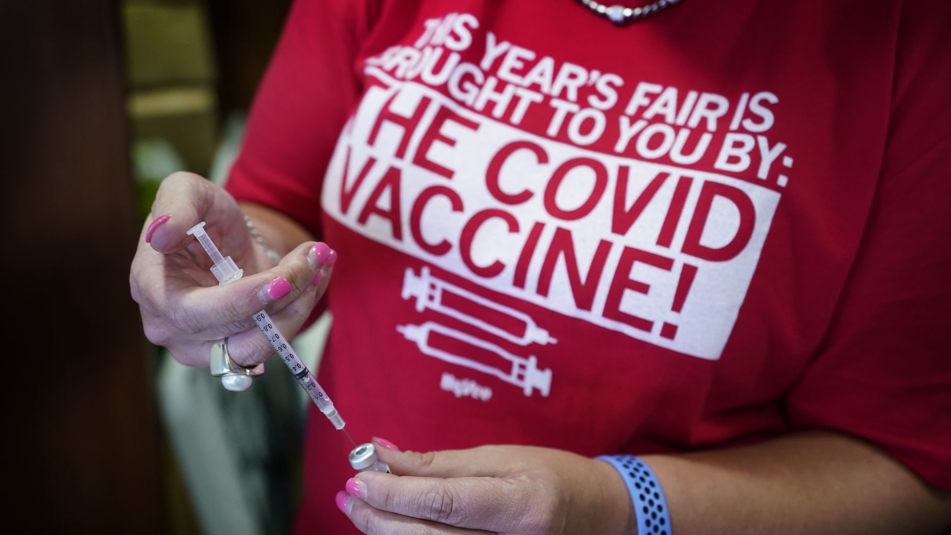 A pharmacist fills a syringe for a COVID-19 vaccination