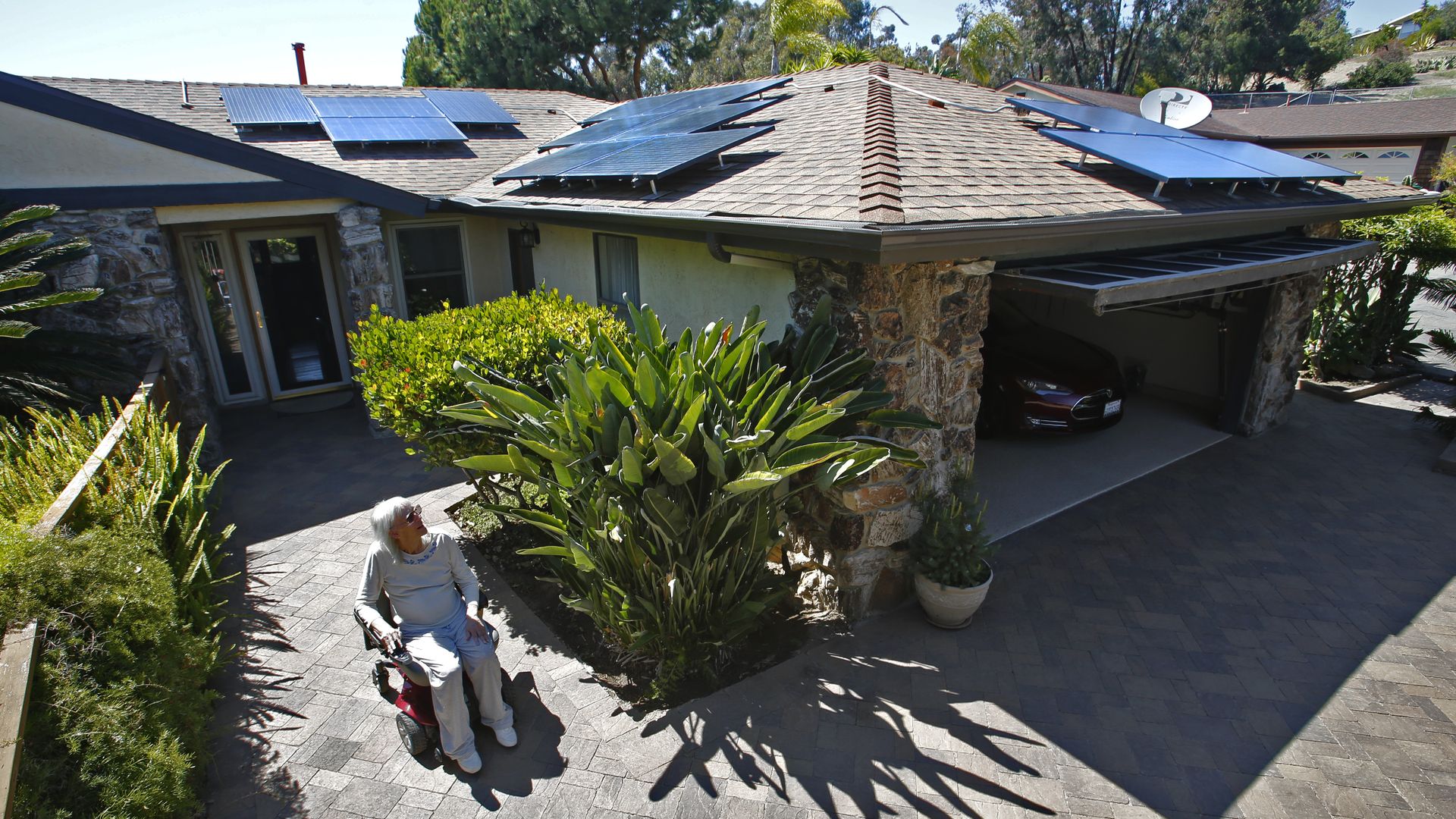Woman cruises around her Oceanside home that has enough solar collectors on the roof to charge her wheelchair, her electric car and run all the household appliances.