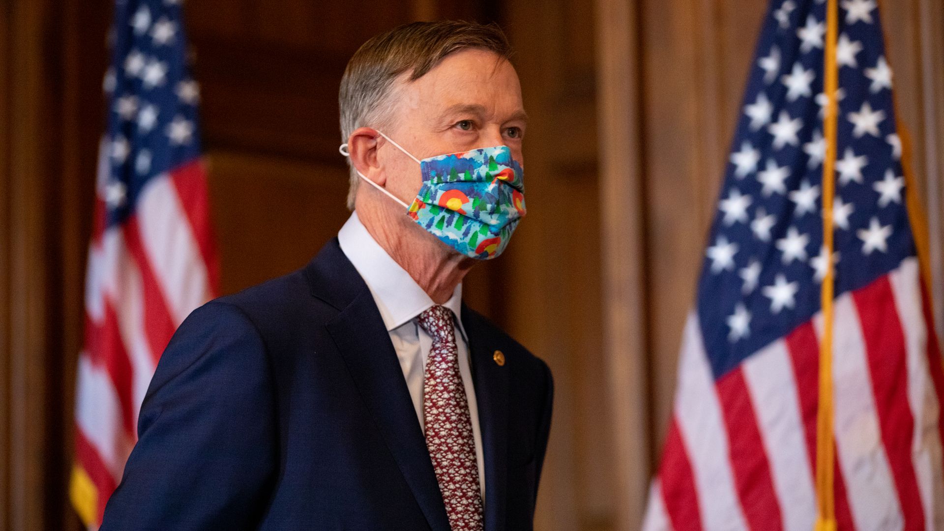 Sen. John Hickenlooper is seen standing during a news conference.