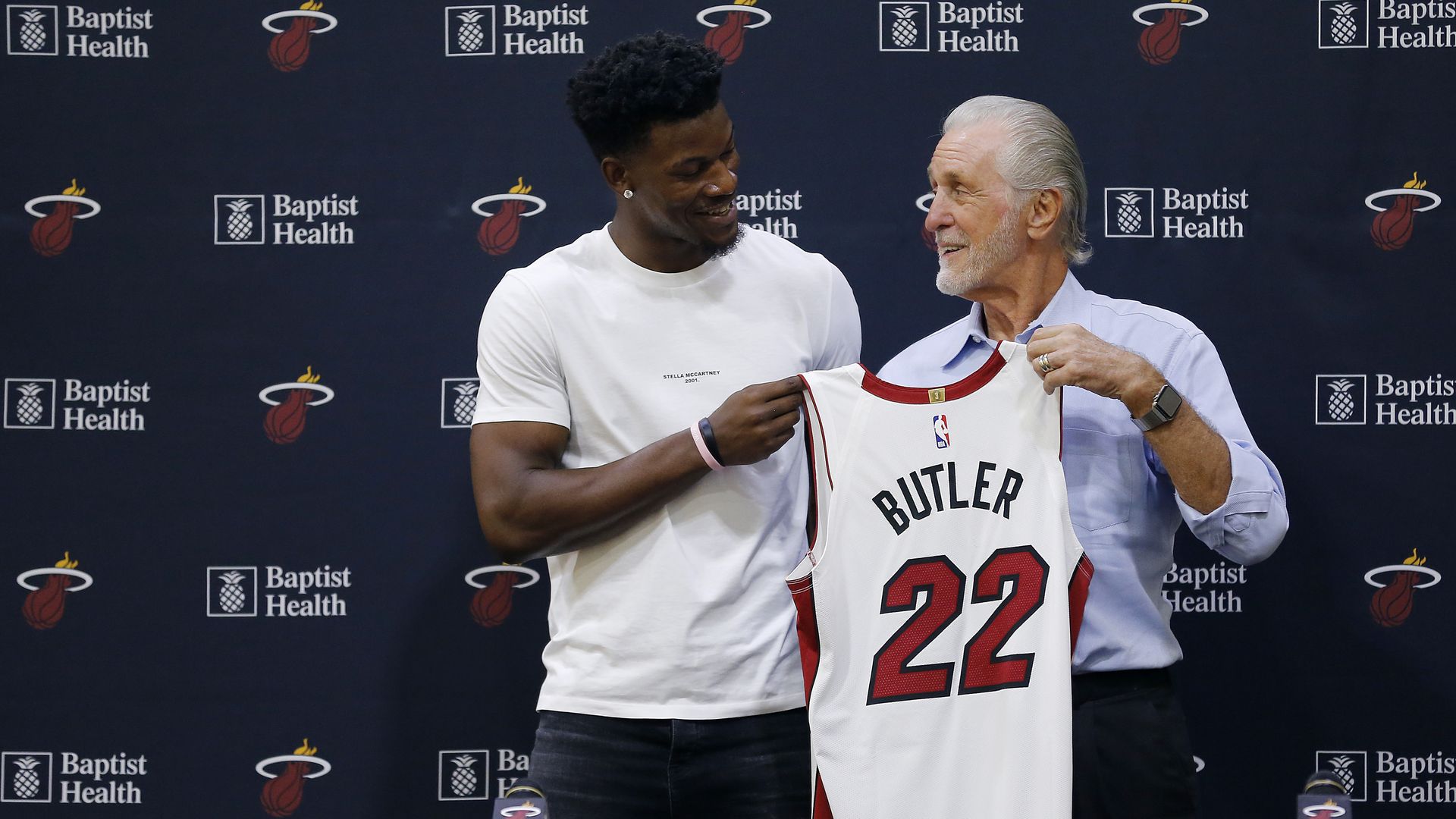Pat Riley and Jimmy Butler holding his jersey. 