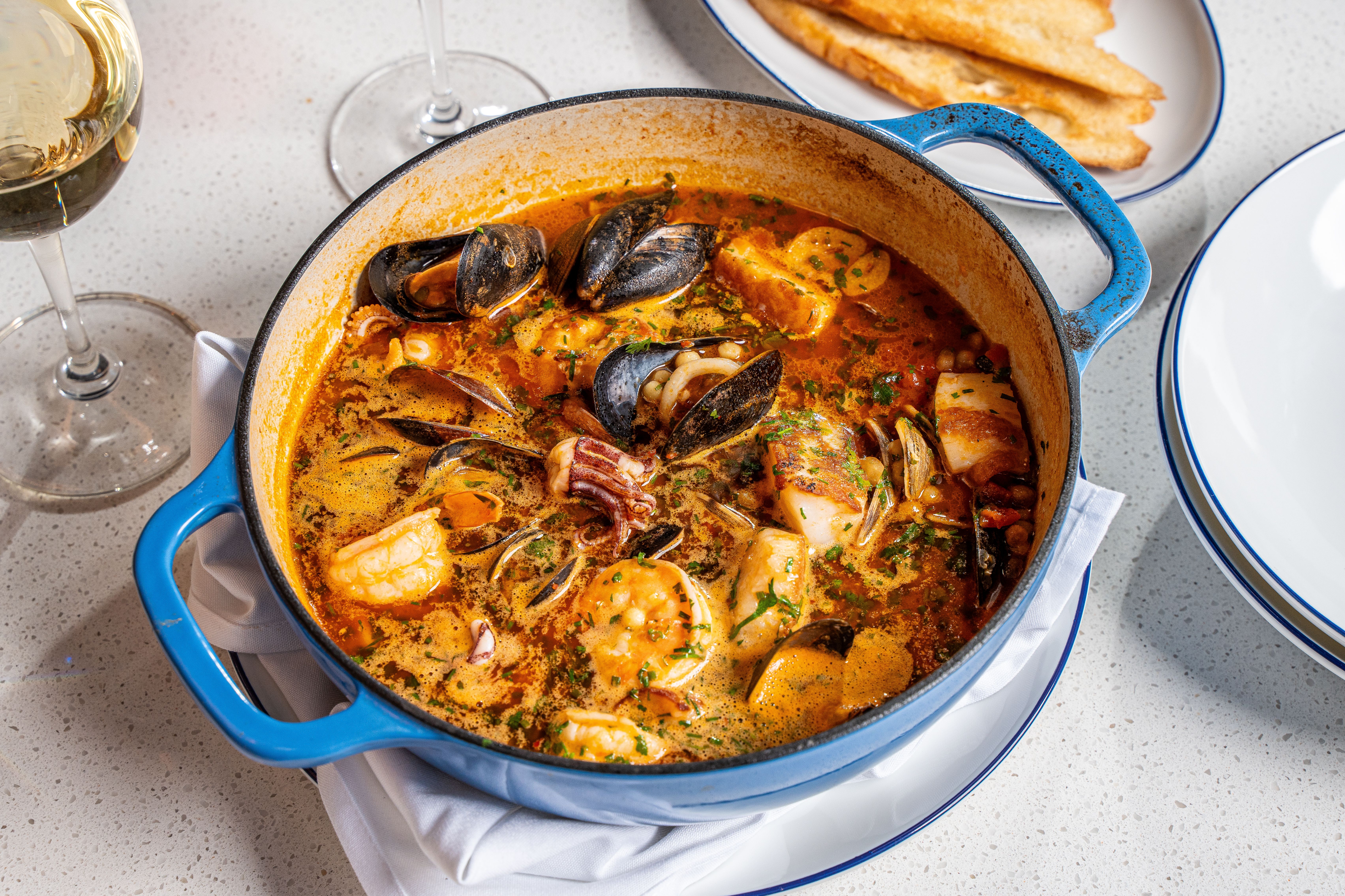 A pot filled with seafood stew with shrimp, mussels, calamari and scallop.