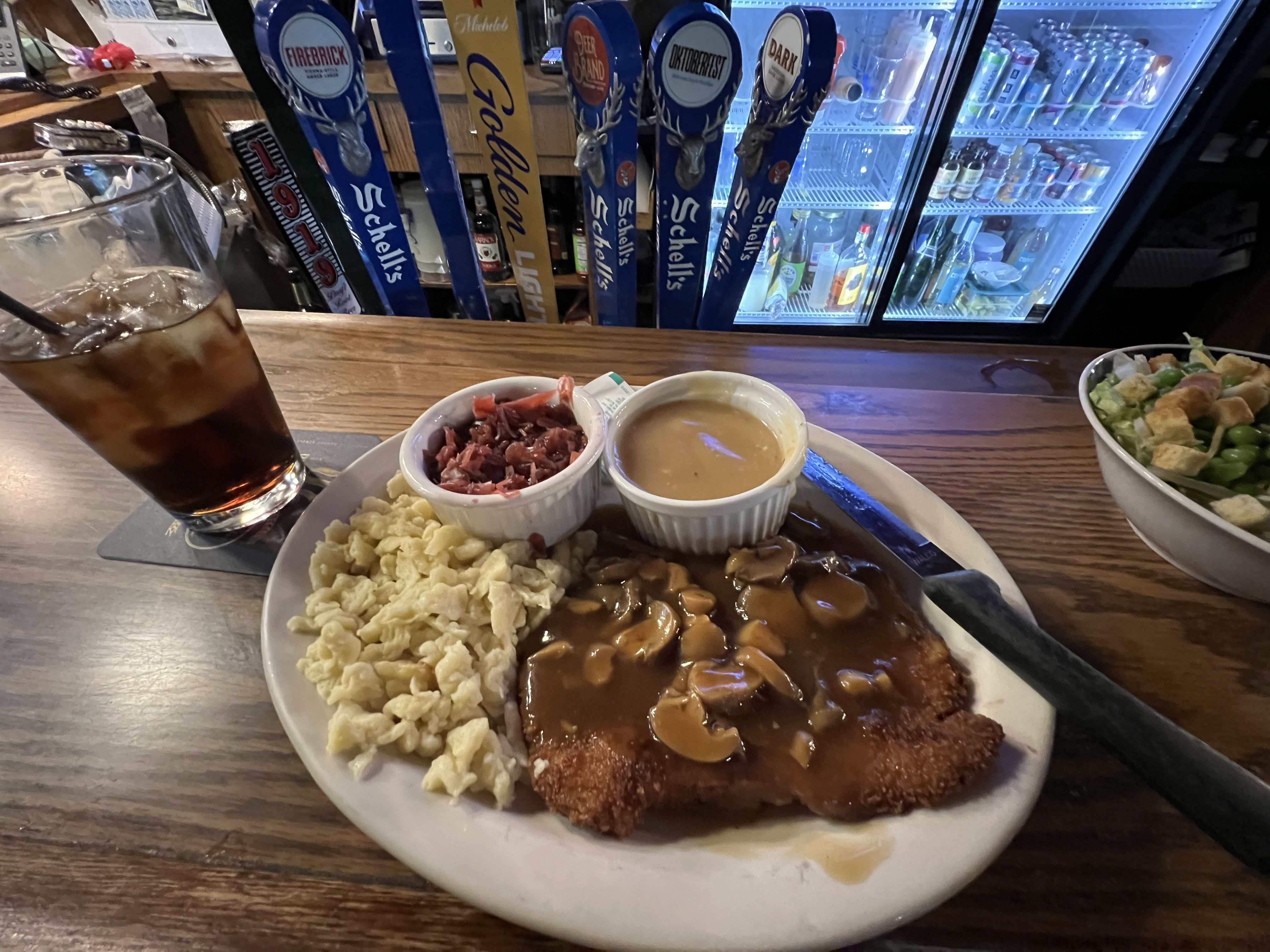 A plate of schnitzel with spaetzle, gravy and red cabbage.
