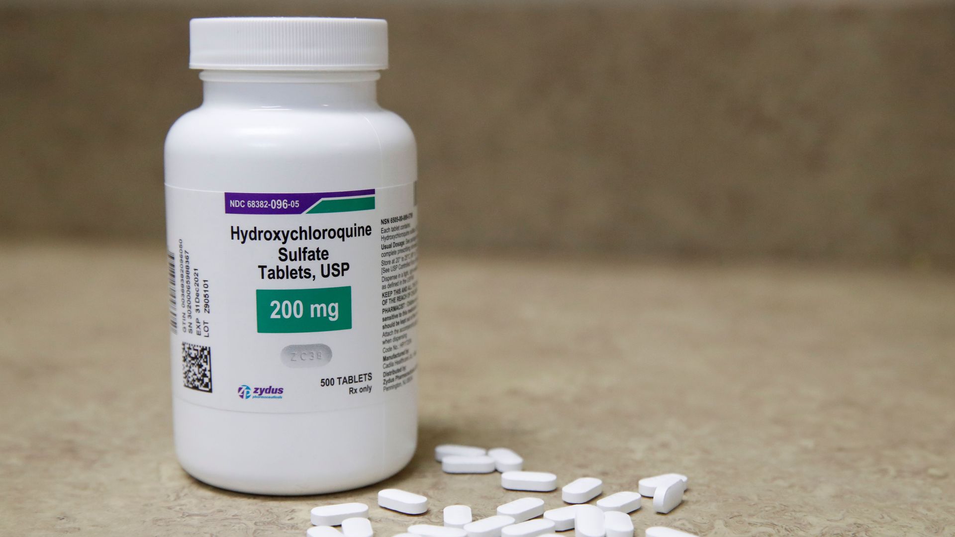 A white bottle of hydroxychloroquine and white pills on a table.