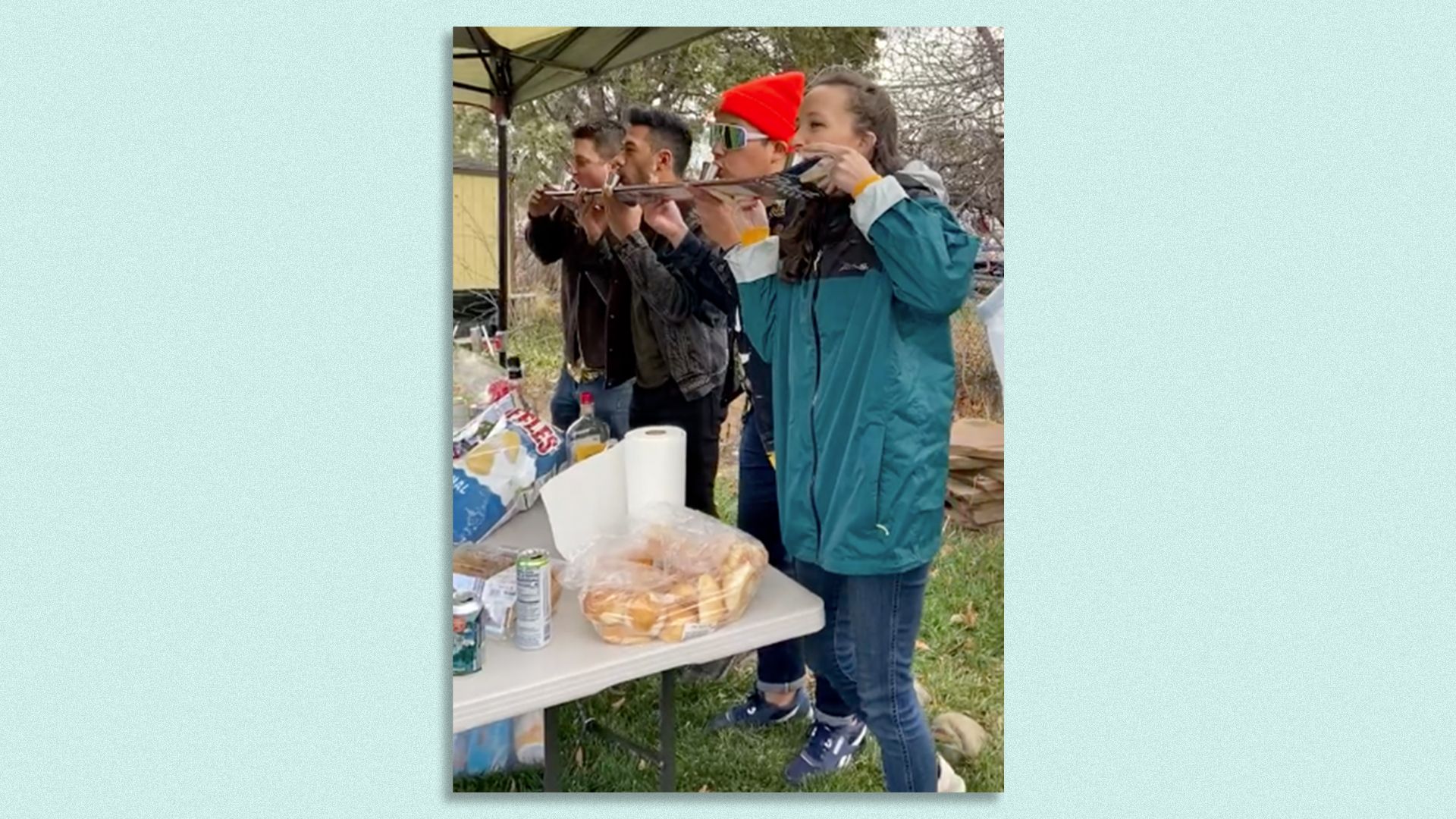 Four partying young adults drink shots of alcohol off a snow ski
