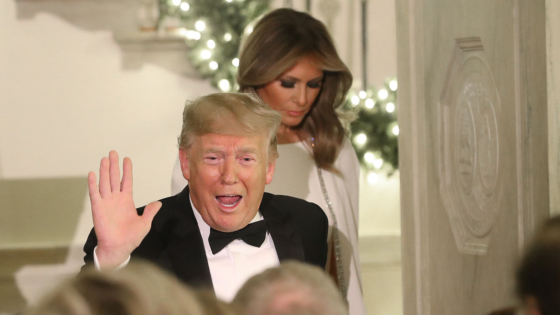 President Donald Trump waves to guests at the Congressional Ball at the White House as First Lady Melania Trump stands behind him.
