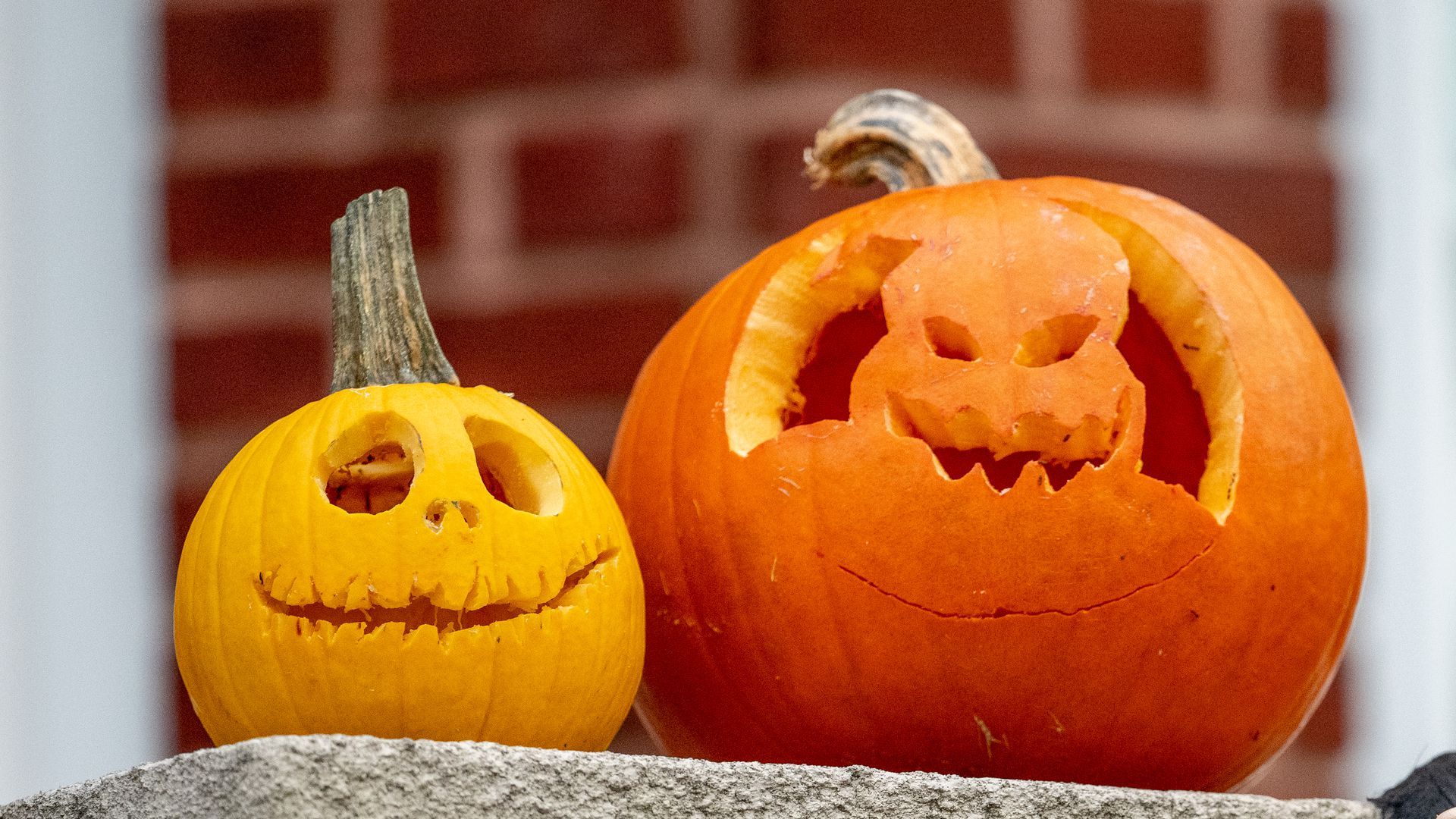 Two Jack-o-Lanterns sitting on a stoop.