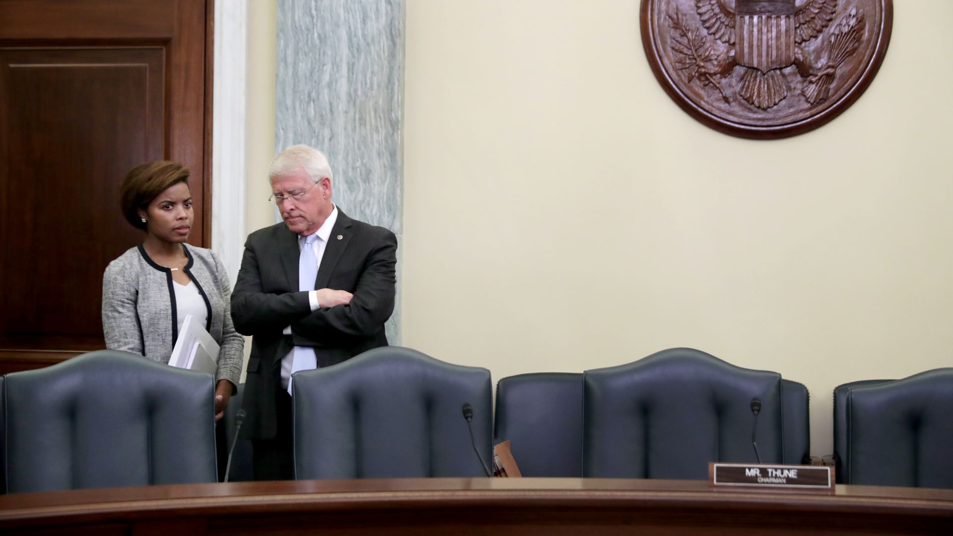 A man and a woman stand together behind a row of chairs