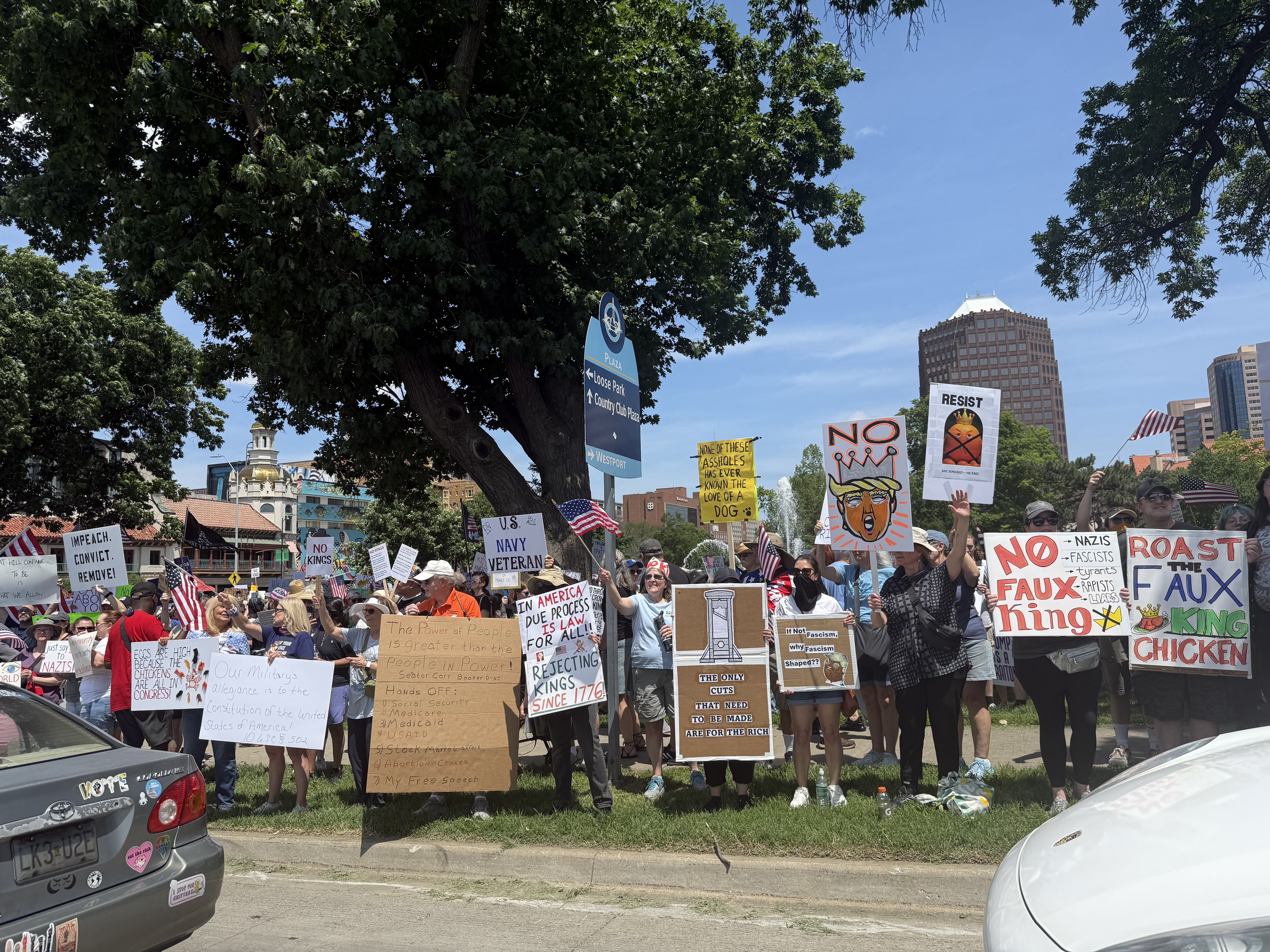 Photo shows protesters at a "No Kings" rally near the Plaza in Kansas City holding signs out toward traffic.