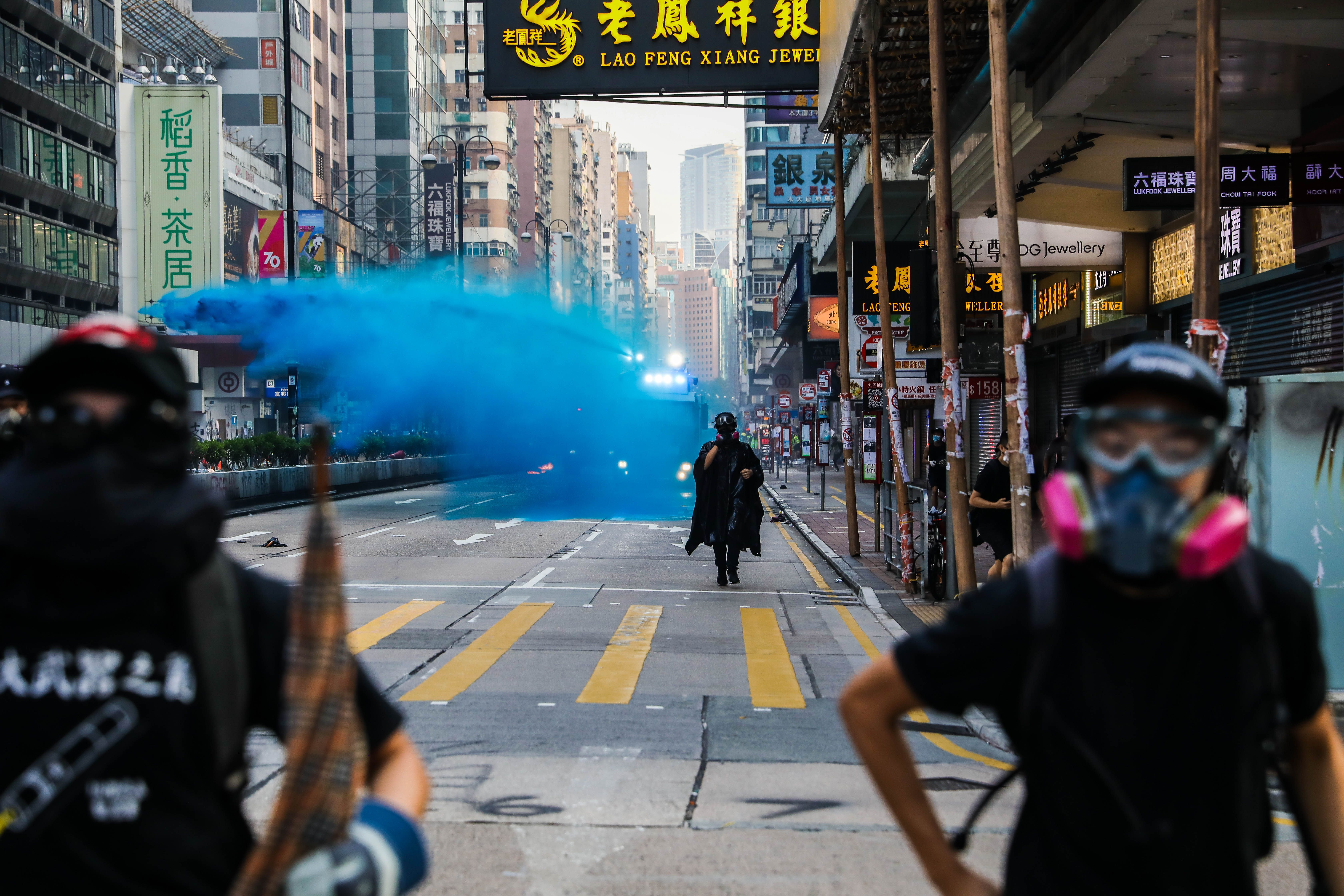 Police deploy a water cannon loaded with a blue irritant.