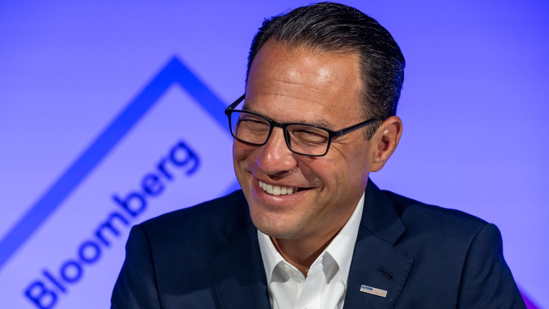 Pennsylvania Gov. Josh Shapiro smiles in front of a purple "Bloomberg" logo in the background.