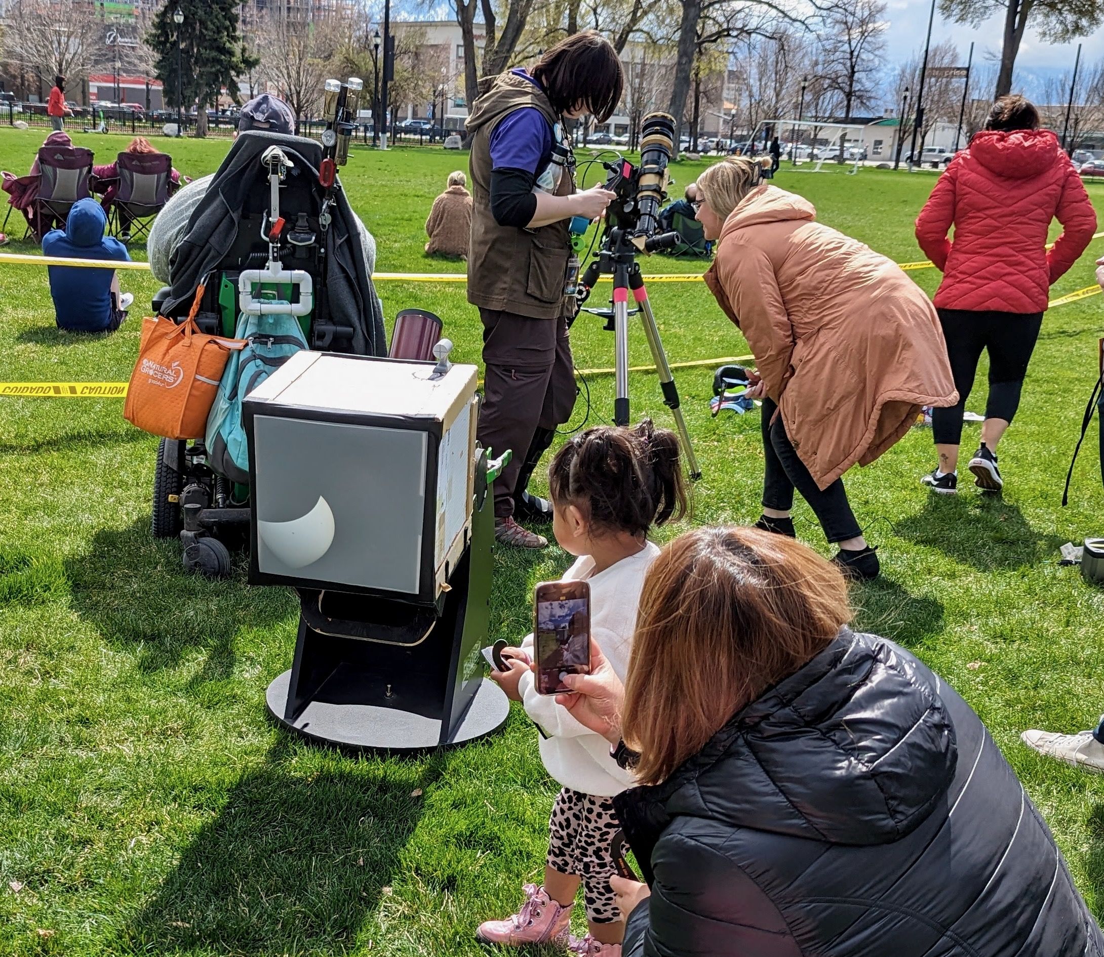 A young child looks at the shadow of the sun and moon on a box projector during a partial eclipse 