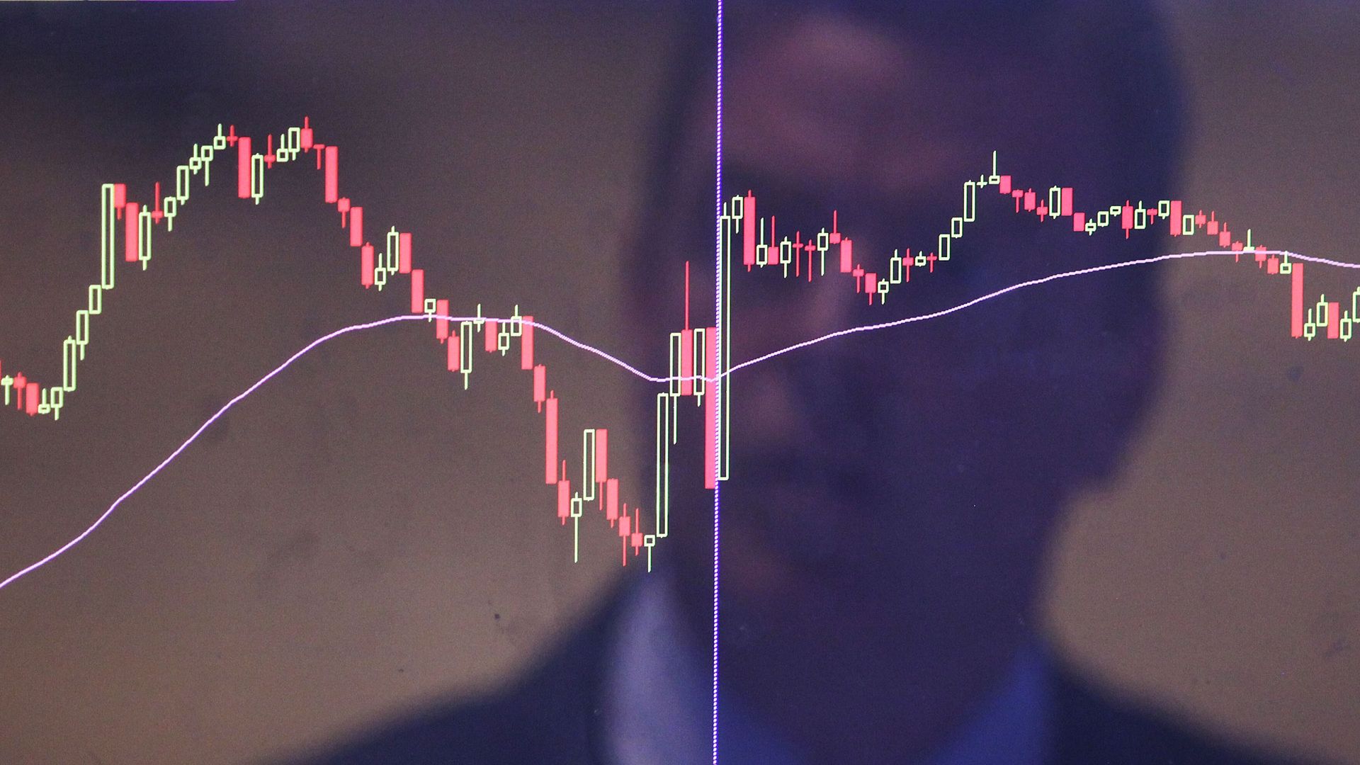 A trader is reflected in a market screen on the floor of the New York Stock Exchange