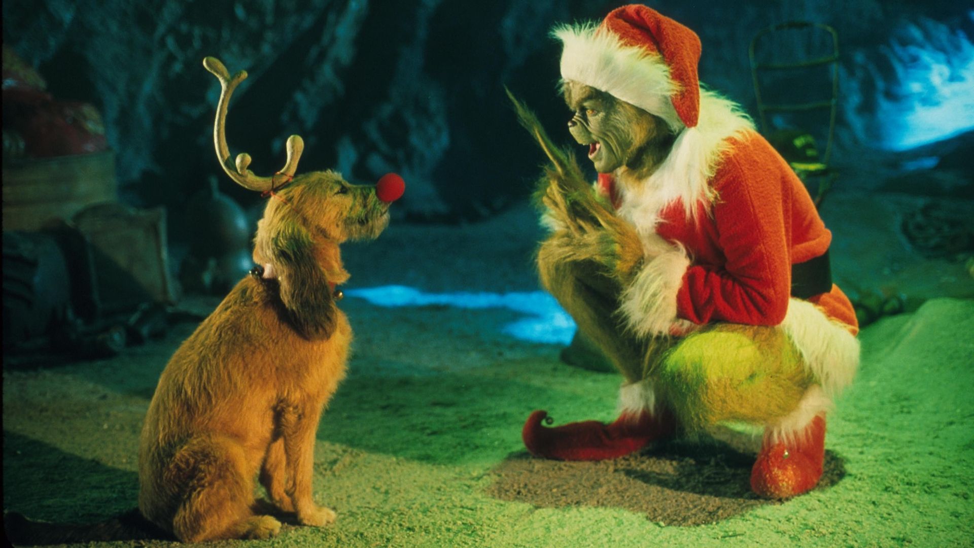 The Grinch, played by Jim Carrey, crouches down to talk to his dog, Max, wearing an antler and red nose in the live-action film "Dr. Seuss' How the Grinch Stole Christmas."