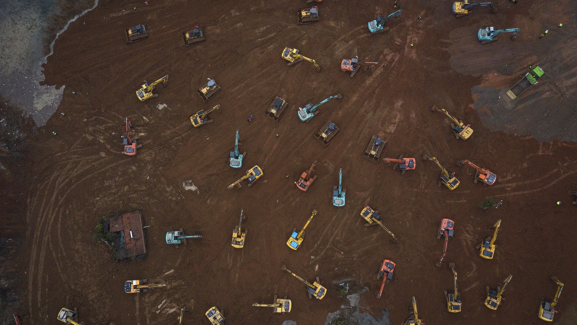 In this image, a field of cranes drive through a dirt field. 
