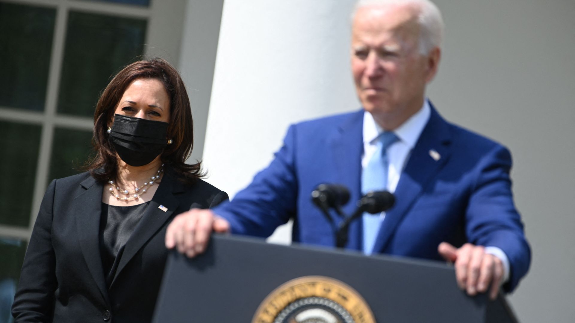 Photo of Kamala Harris standing next to Joe Biden as he speaks from behind a podium