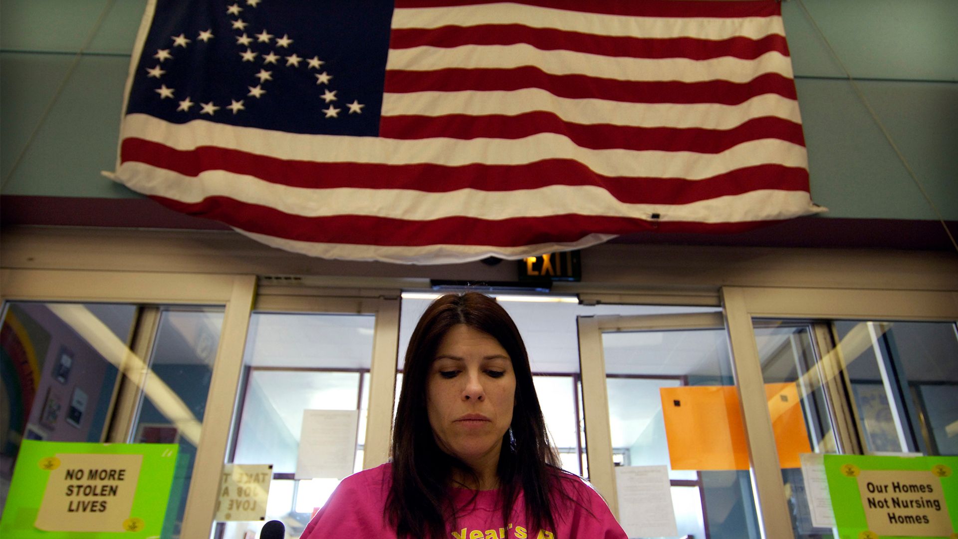 A woman looking down with ADAPT's flag hanging above her.