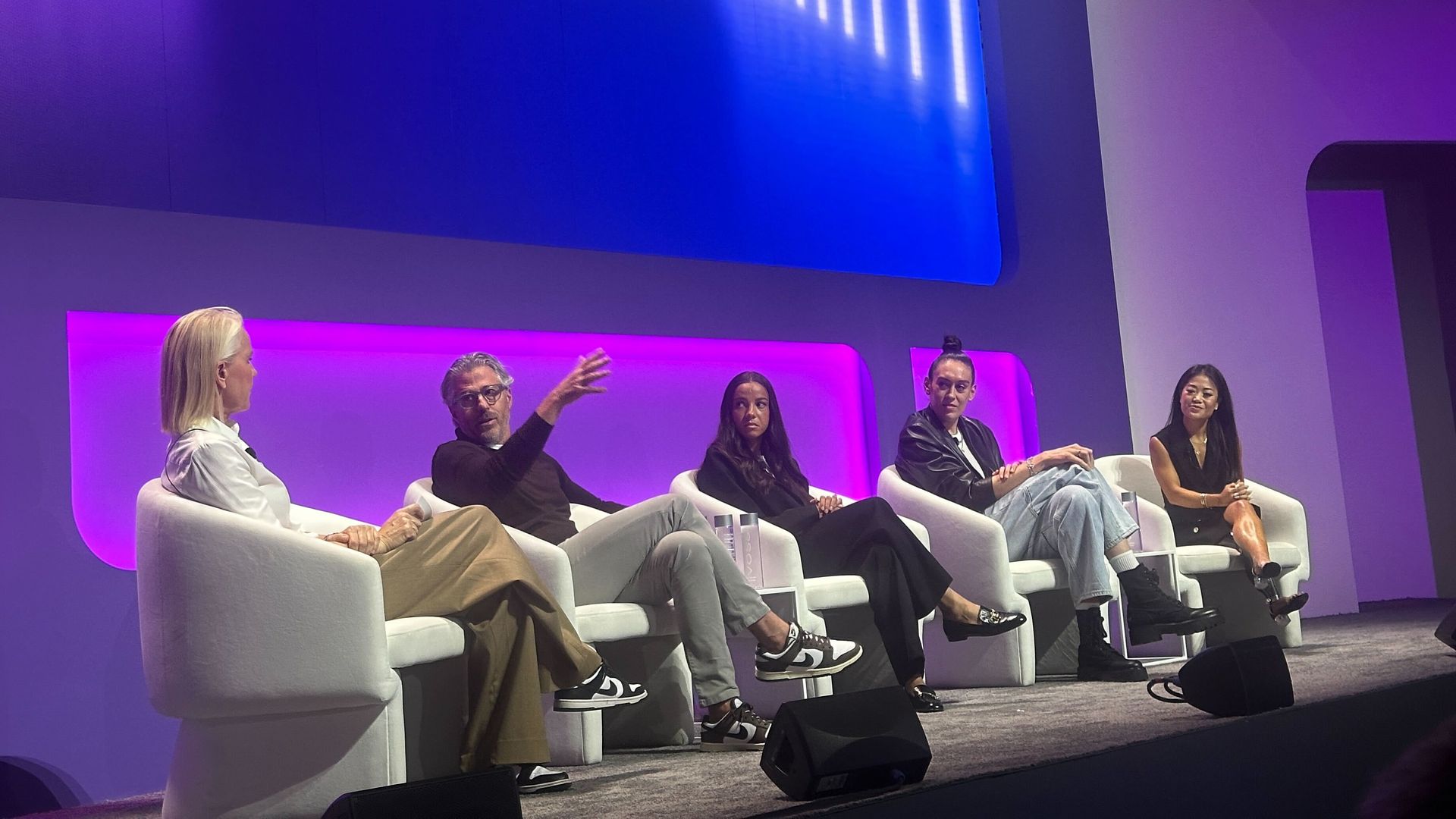 Rennae Stubbs, Casey Wasserman, Mallory Swanson, Breanna Stewart and Scout Bassett sitting in white chairs on a stage with the background lit in purple