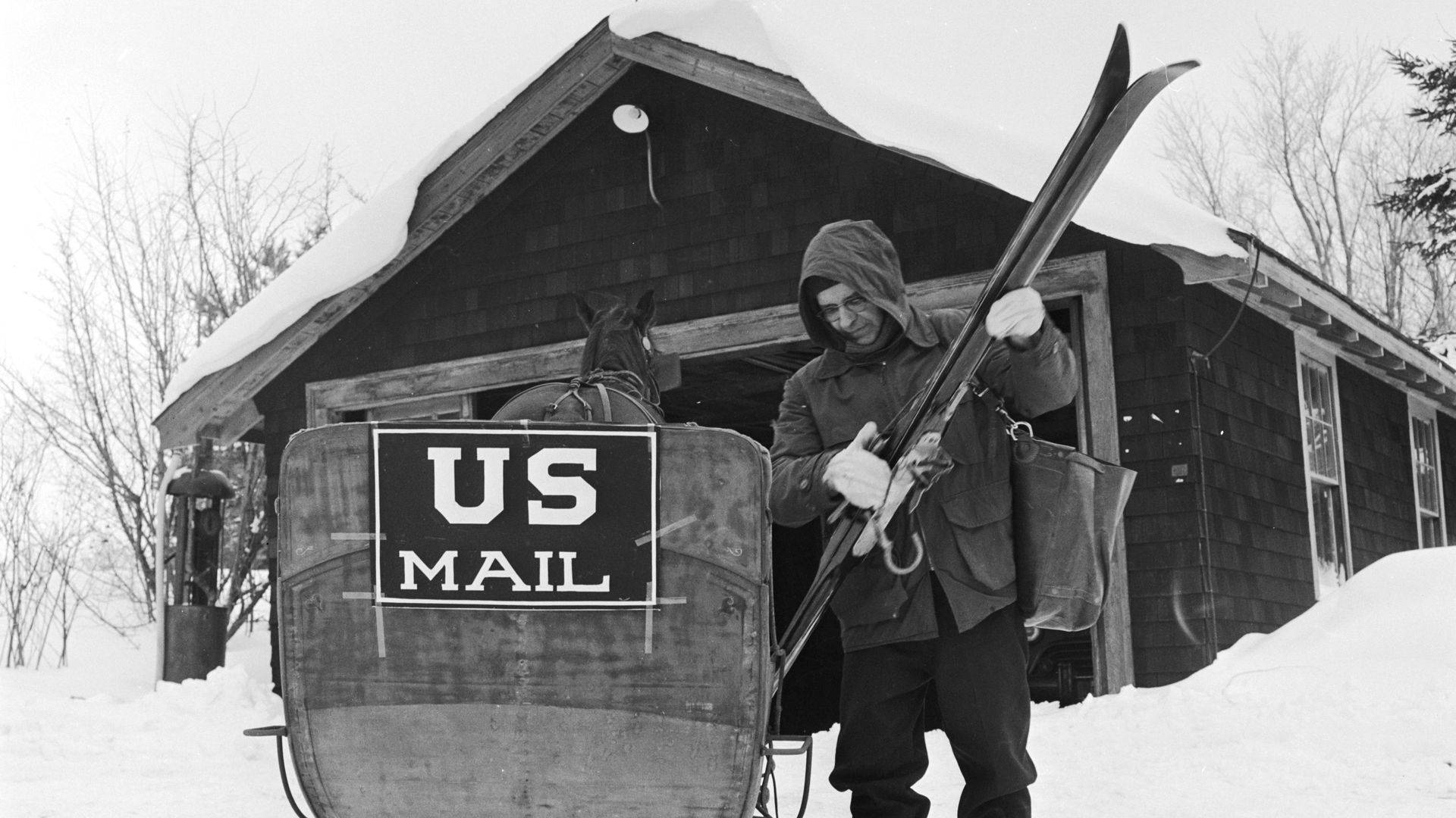 Photo of a postman with skis by a mail sleigh