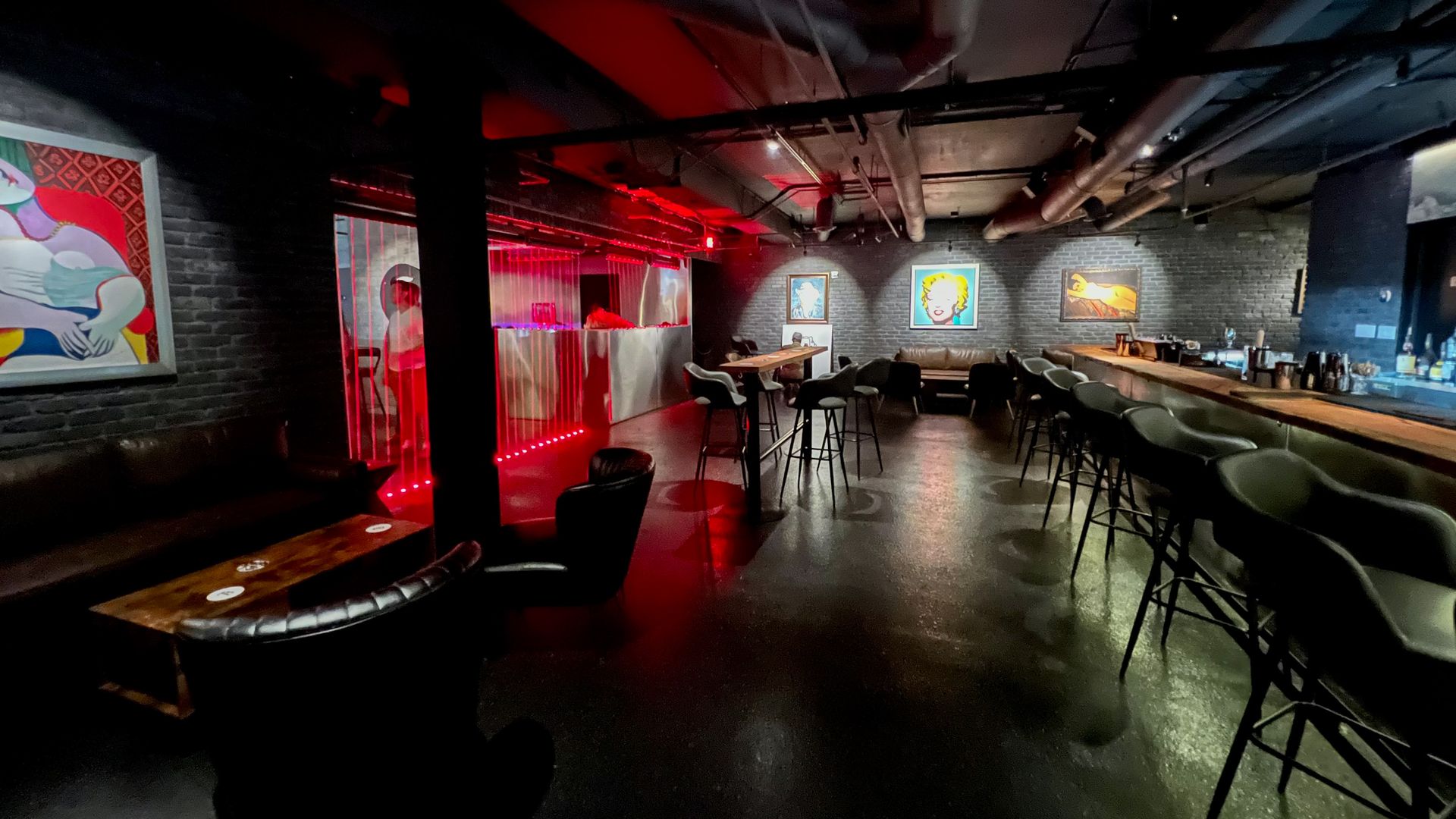 A dimly lit bar with classic paintings covering the walls. 