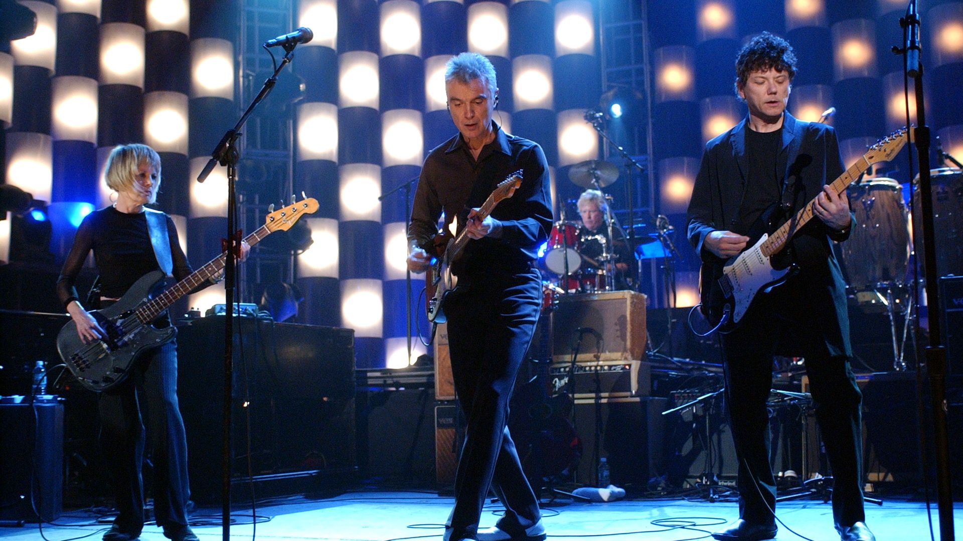 Tina Weymouth, David Byrne, Chris Frantz and Jerry Harrison of Talking Heads perform on stage.
