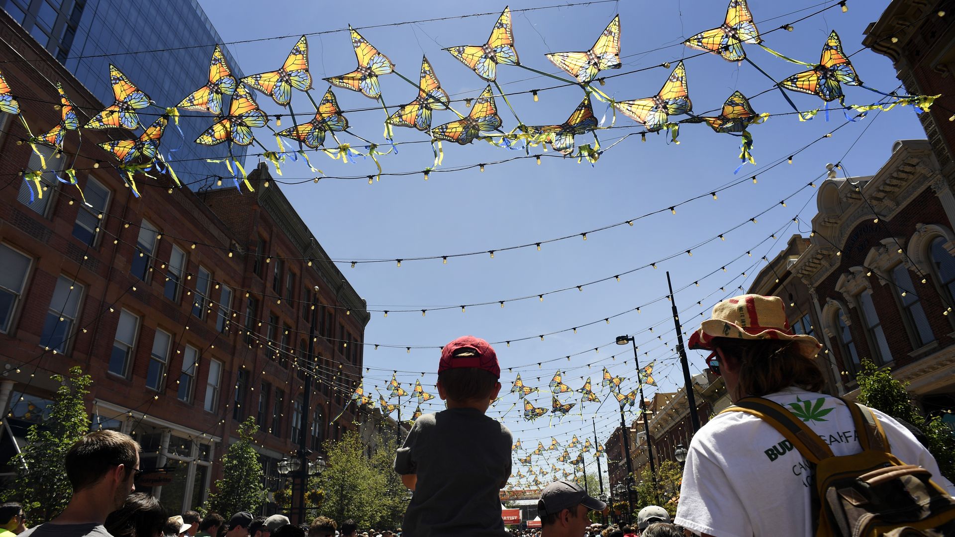 A child on a man's shoulder looks on. 