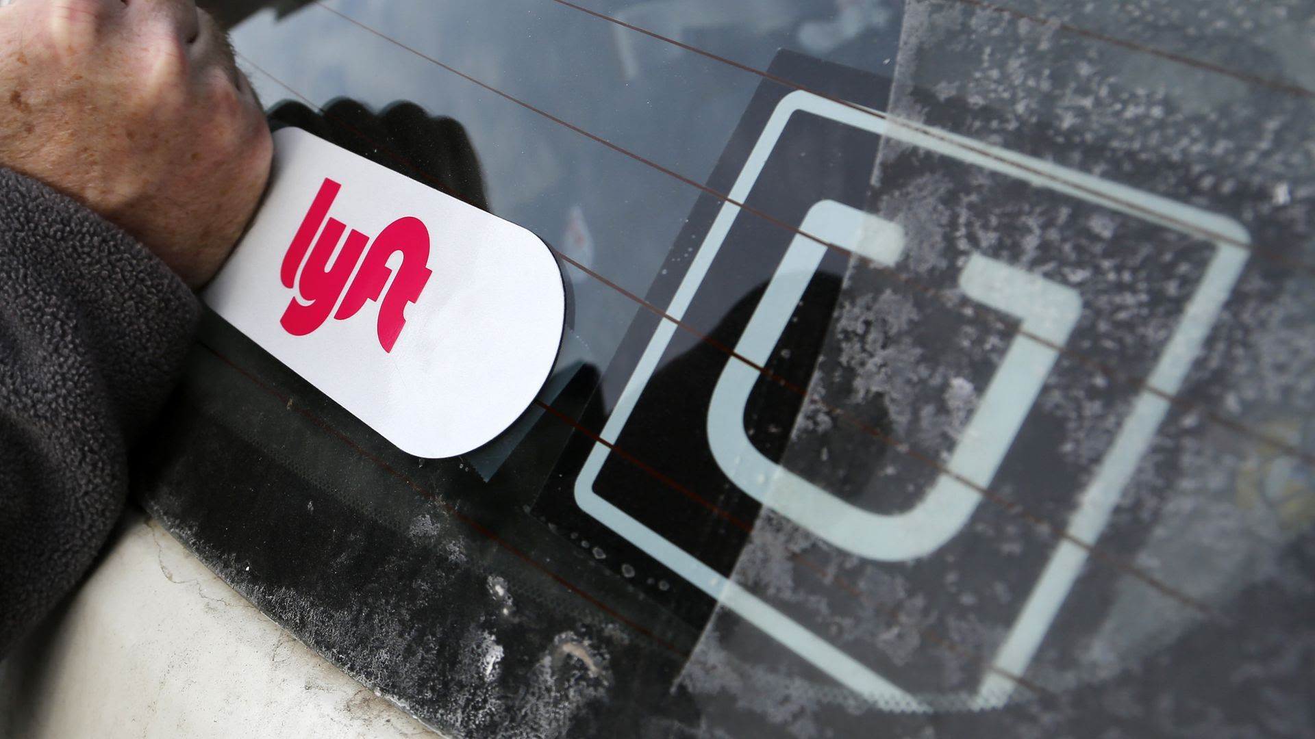 Uber and Lyft stickers on a car.