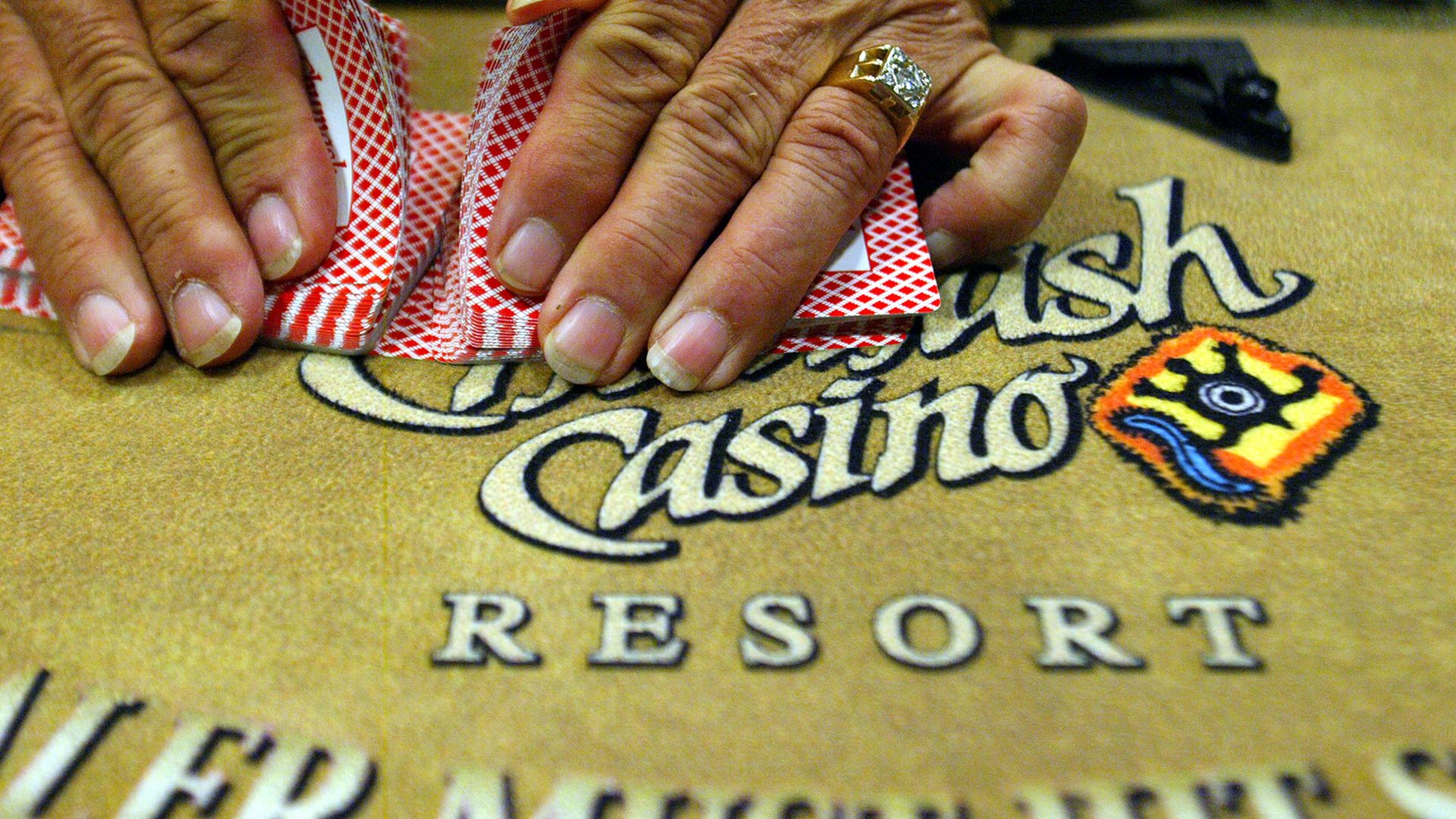 Photo of hands dealing cards on a table with the words "Casino Resort" embroidered in it